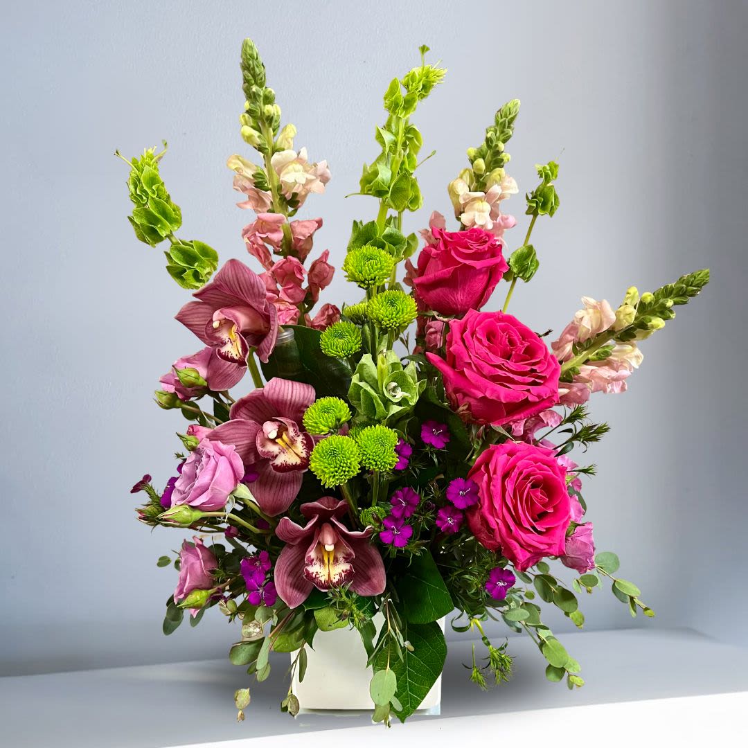 Take Me Away by BloomNation - Escape to paradise with this lush and vibrant bouquet. This arrangement contains Cymbidium Orchids, Bells of Ireland, Snapdragon, Roses, Pink Spray Roses and Button Mums. This is the perfect gift for a birthday, congratulations, or to celebrate new beginnings. APPROXIMATE DIMENSIONS: 16" H x 13" L x 13" W