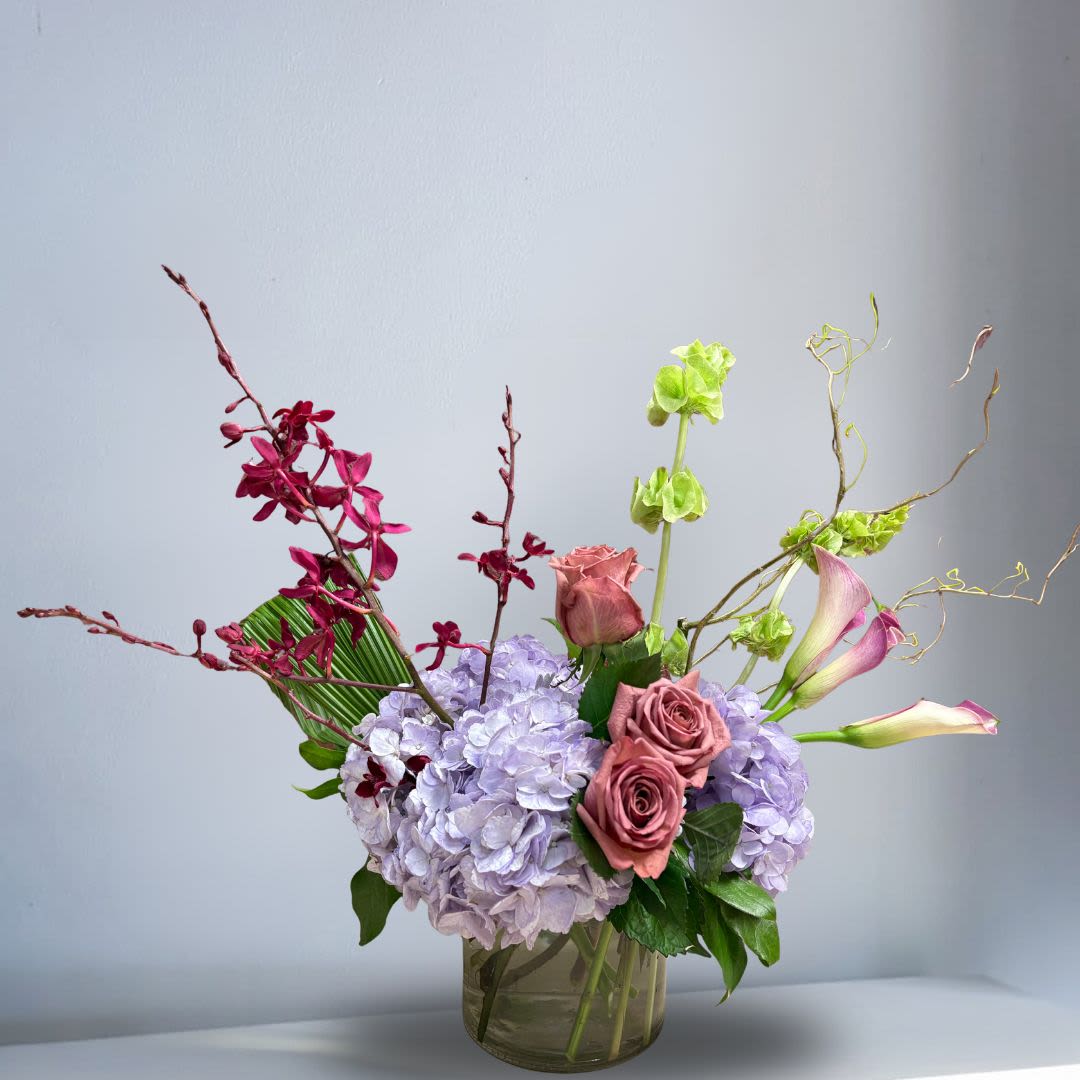 Modern Japanese Gardens - Enjoy this Japanese inspired, simple and modern piece with Orchids, Calla Lilies, Mauve Roses, Hydrangaes, and more.