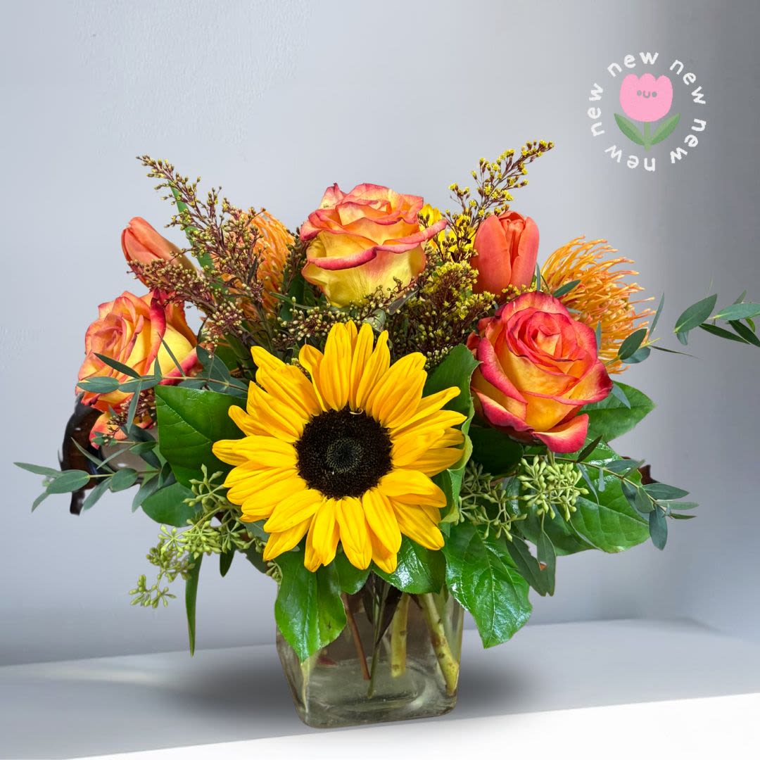 Bouquet of yellow sunflowers and orange roses in a glass vase