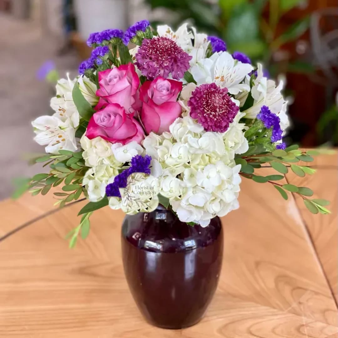Pink roses and white flowers arranged in a dark vase