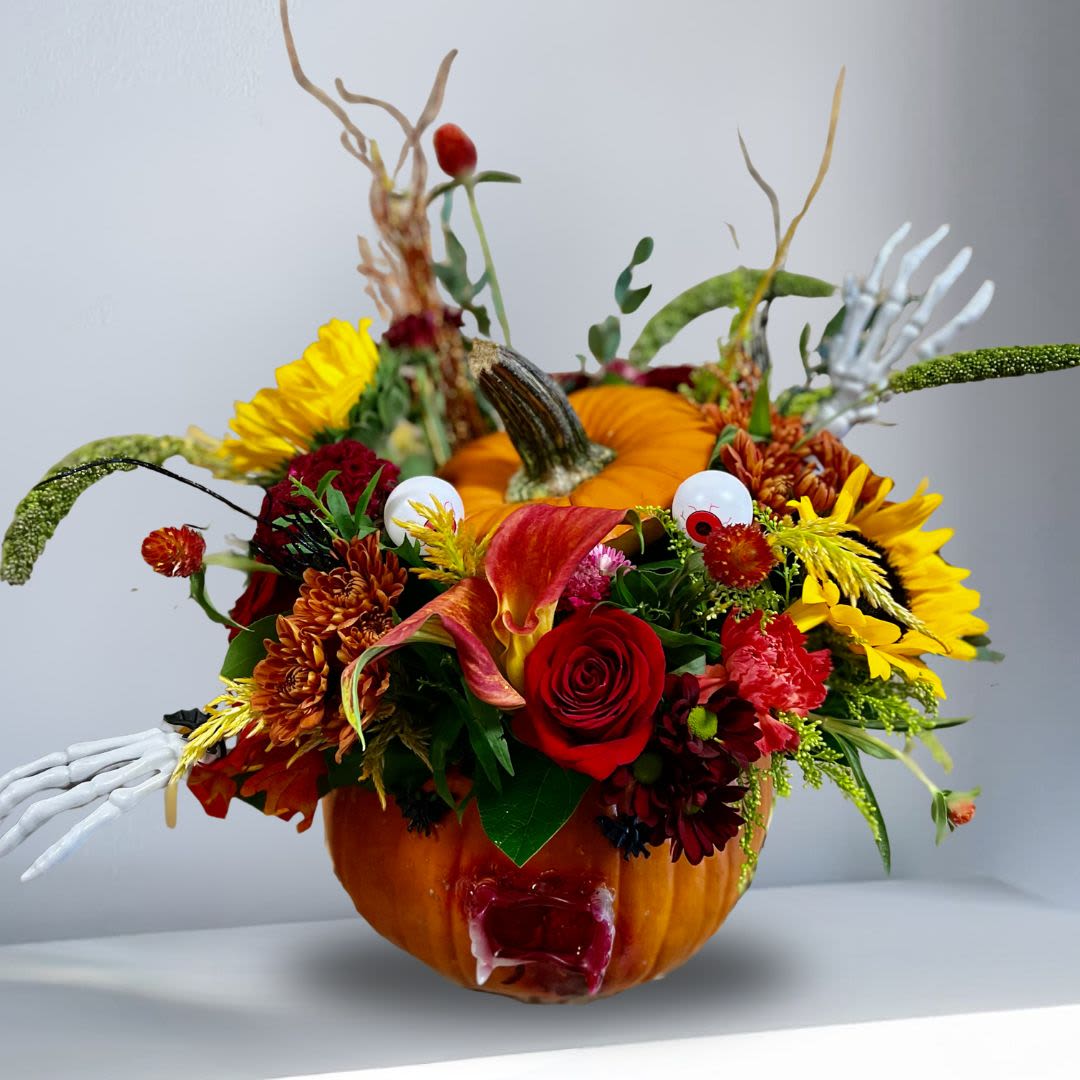 Spook-tacular in Natural Pumpkin - Type Of Flowers: Red Roses, Black Calla Lilies, Sunflowers, Red Carnations, Brown Cushion Pom Poms, with a grueling face on a Natural Pumpkin and more! Availability: October Substitute Available: Yes Design View: Asymmetric Front Facing View Photo shown: Regular