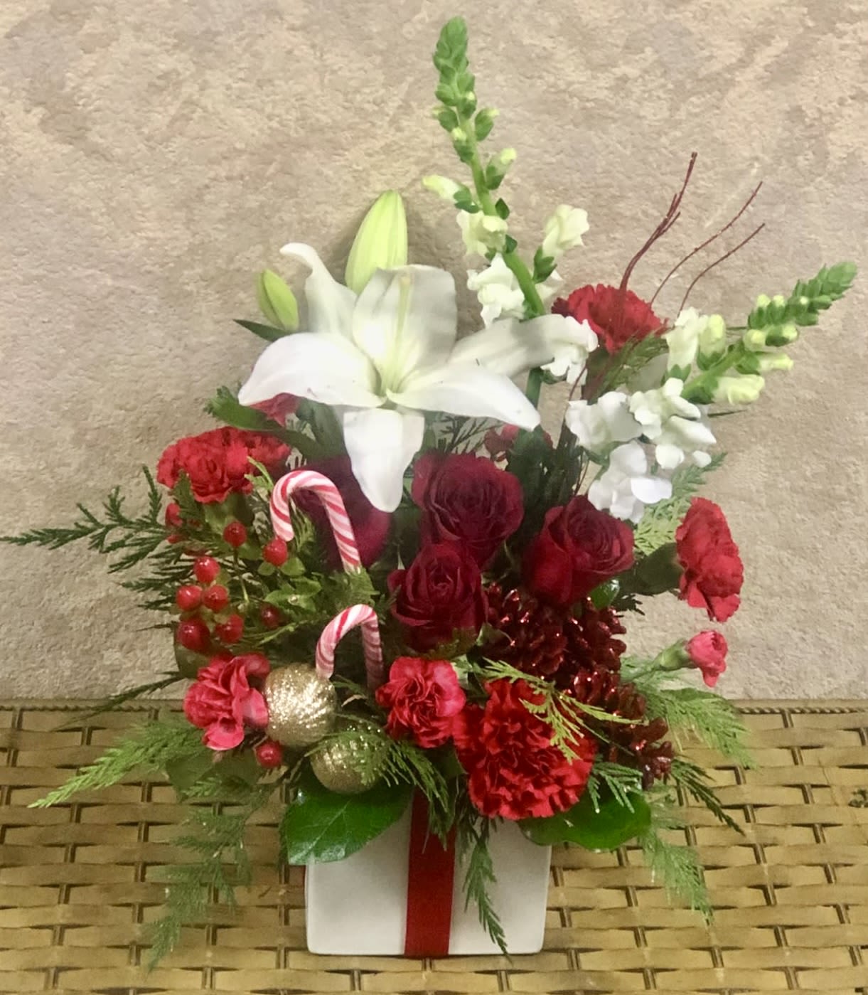 North Pole - Recipe: Asiatic White Lilies, White Snapdragons, Red Carnations, Red Roses, and Pine Branches with Pine Cones, Ornaments and Candy Canes. Availability: Winter Orientation: Front Facing View Photo shown: Standard