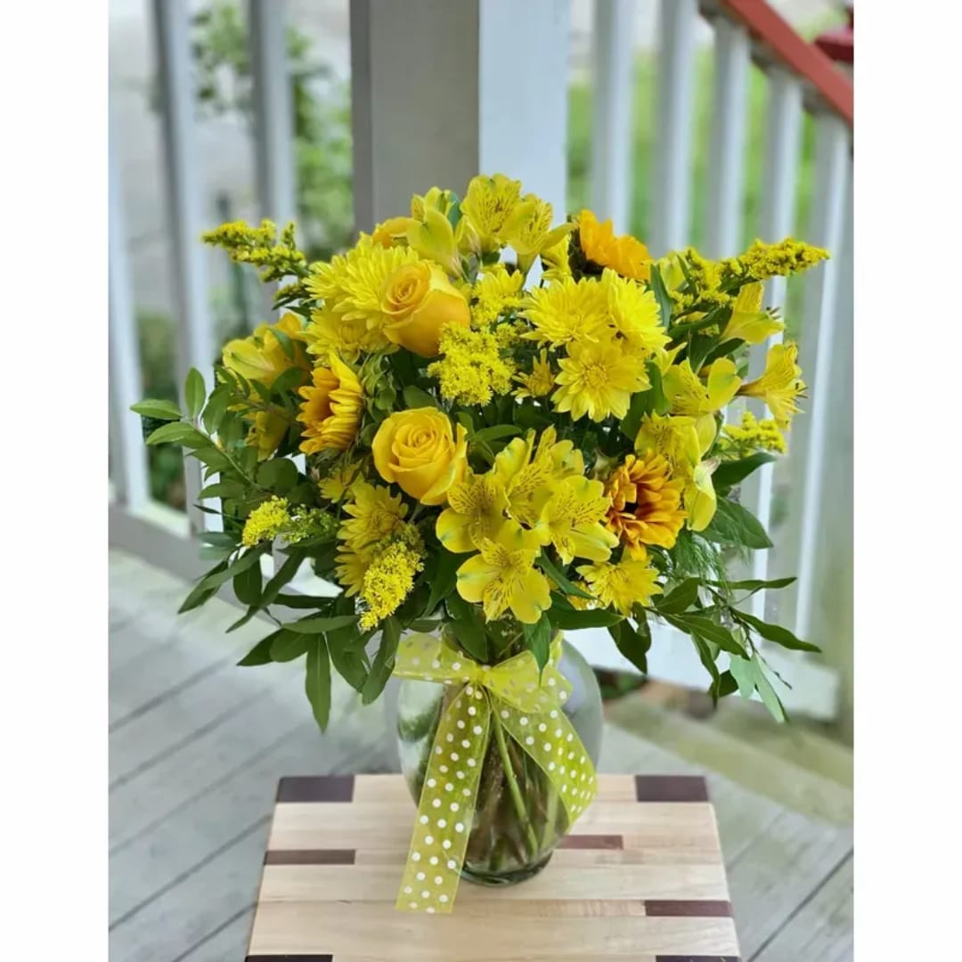 Yellow mixed bouquet in a glass vase with a polka-dot ribbon
