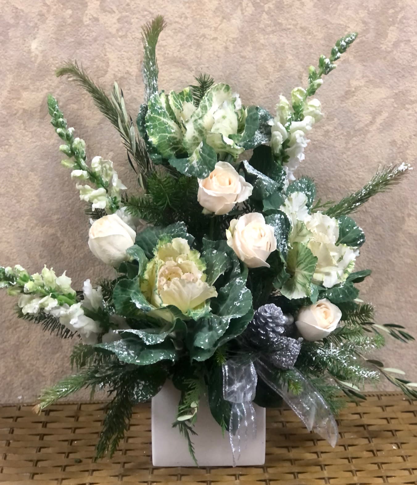 Let it Snow - Type Of Flowers: White Roses, Snapdragons, and Kale with Ornaments, pine cones and Snowy accents in a square, white, ceramic vase