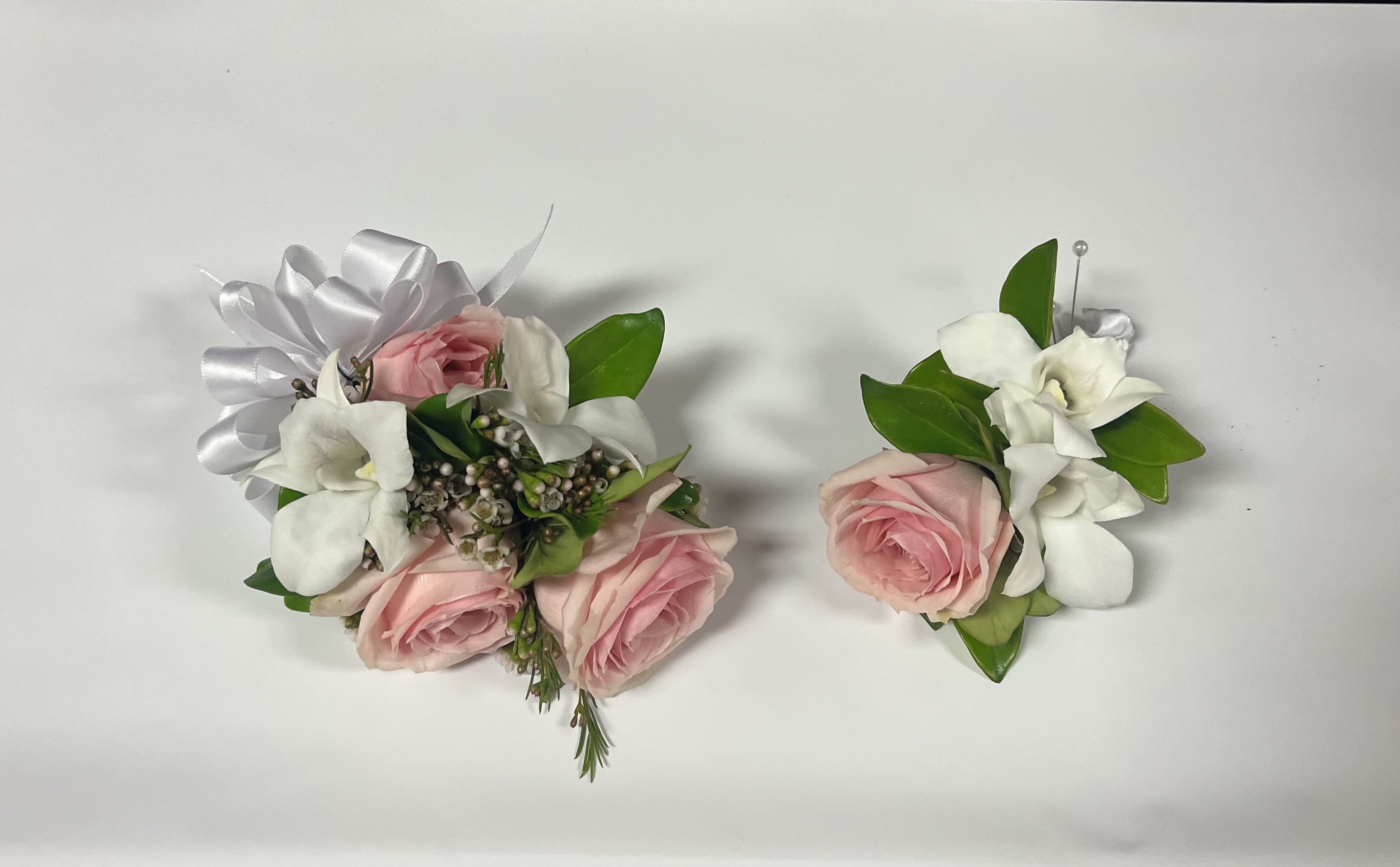 Pink rose and white gardenia wrist corsage and boutonniere set on white background