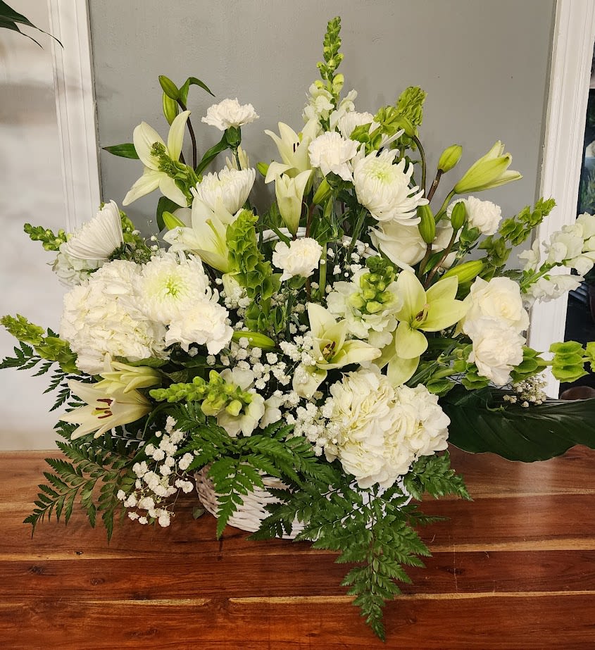 White floral arrangement with lilies, chrysanthemums, and carnations in a basket