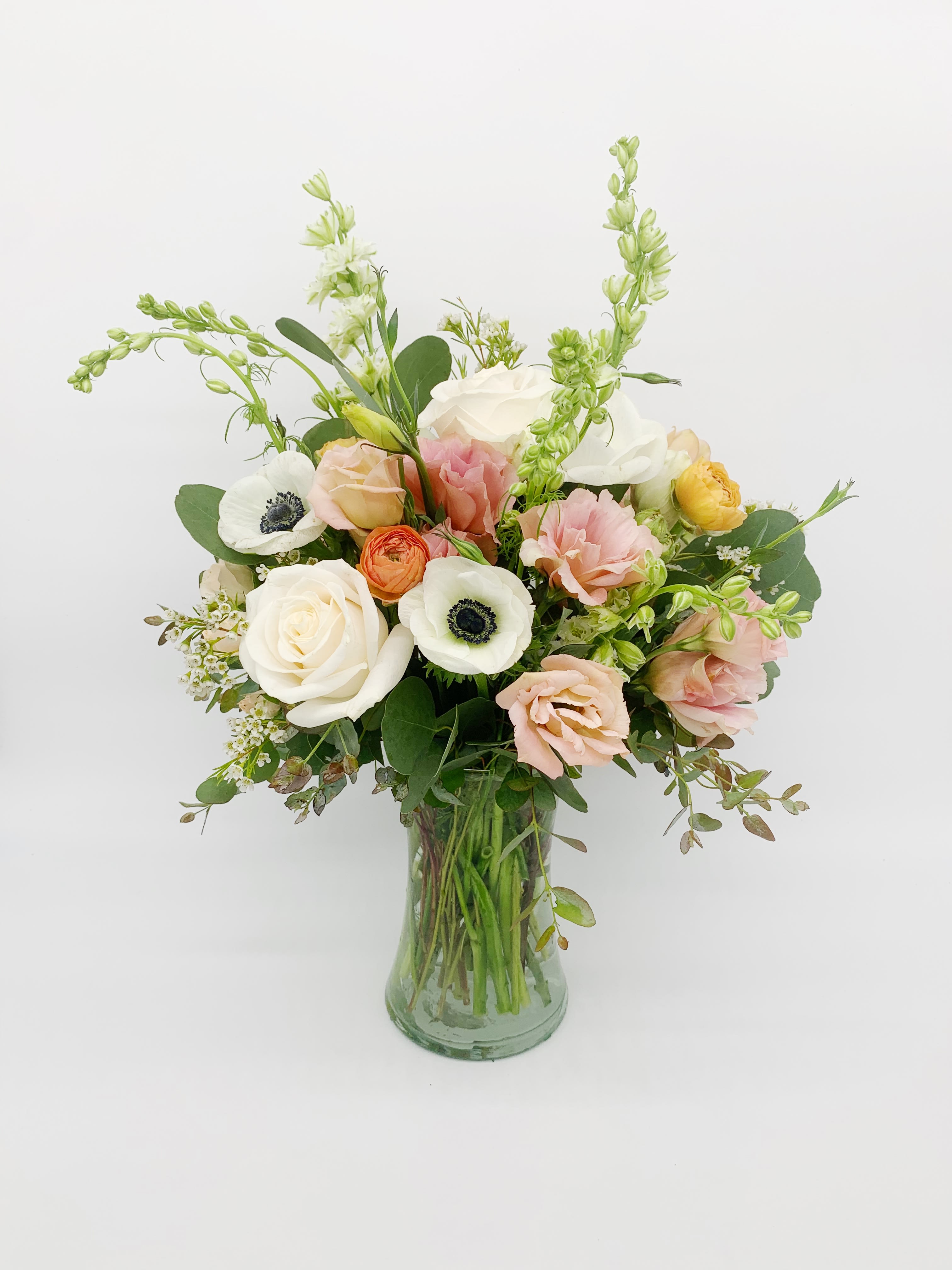 Pastel bouquet of mixed flowers arranged in a clear glass vase.