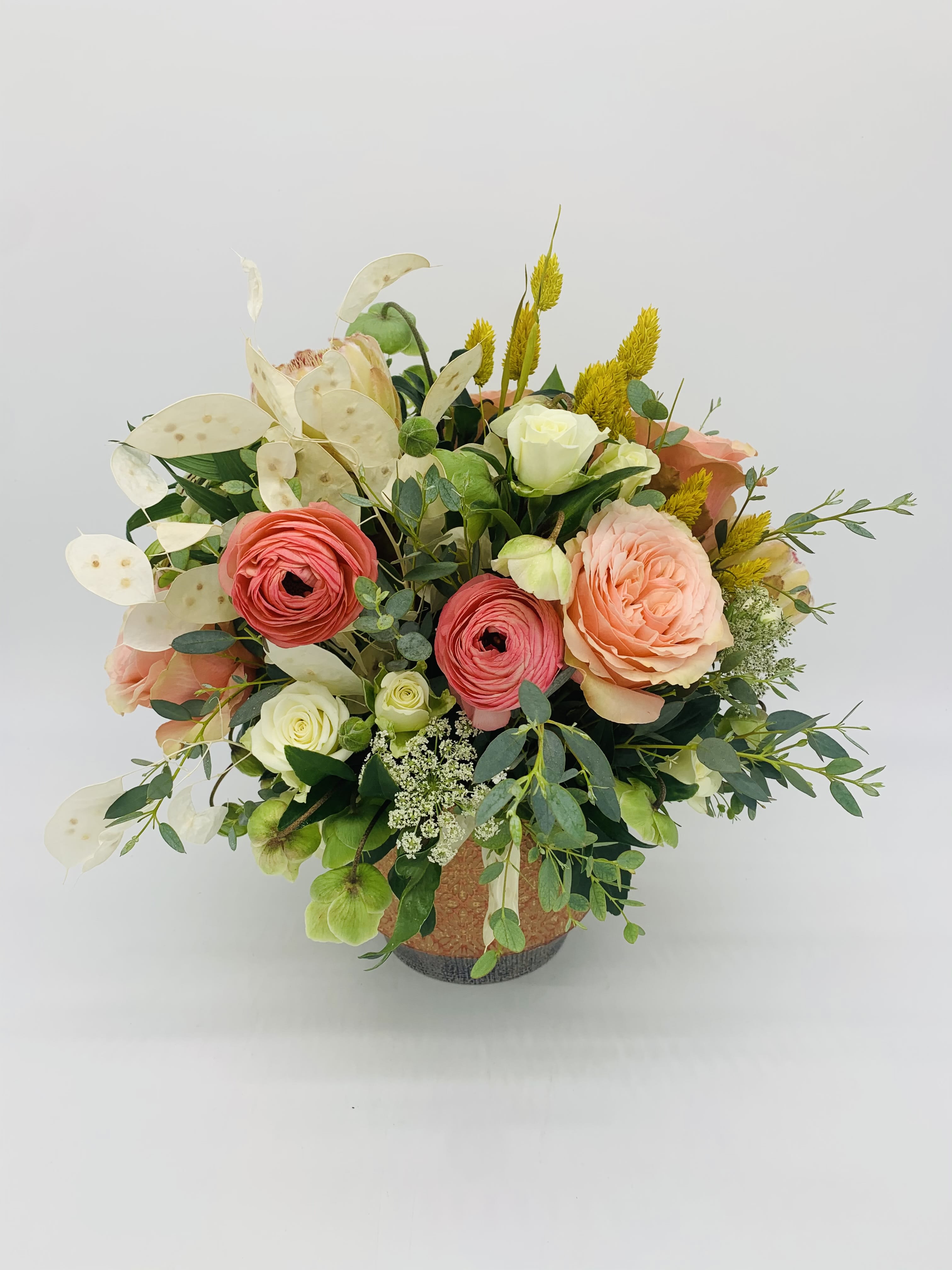 Peach and coral roses with white blooms arranged in a decorative ceramic pot.
