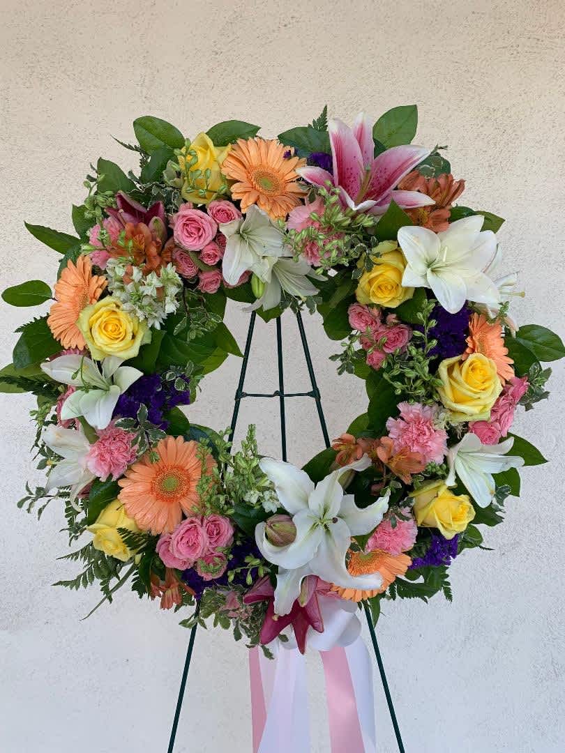 Colorful standing wreath of lilies, roses, gerbera daisies, and carnations on a metal easel