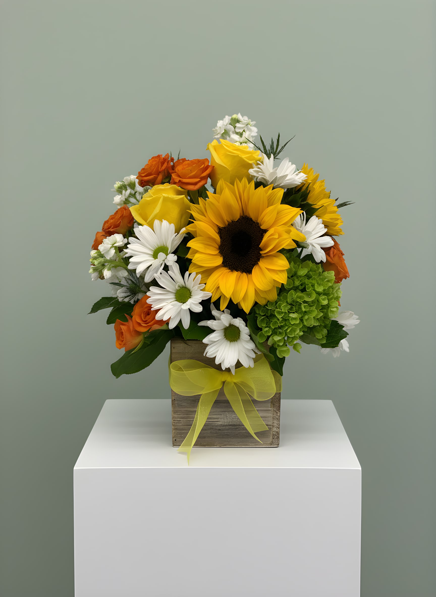 LF98- Sunshiny Day - An ultra cheerful arrangement of yellow sunflowers, orange spray roses, mini green hydrangea and white daisies. Arranged so perfectly in a 5 x 5 white washed wood box with a pretty yellow bow.  This arrangement will bring sunshine to anyone's day!   Orientation:  All-Around Approximately:  14 1/2" H  X 13" W x 8" D