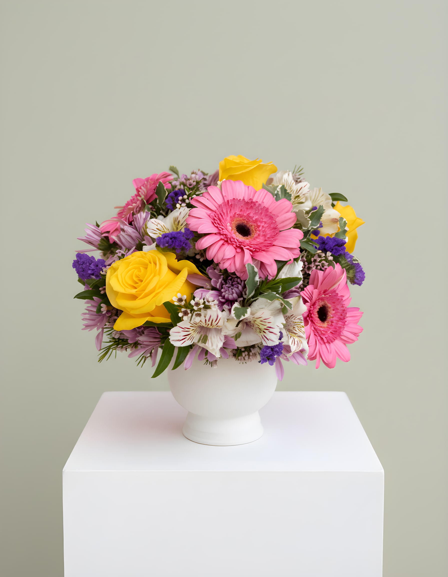LF401 Morning Sunshine - This cheerful Mother's Day arrangement features a lovely mix of soft pink gerbera daisies, vibrant yellow roses, and delicate lavender chrysanthemums. Accented with purple statice and wax flowers, it's all beautifully arranged in a 5X5 white, ceramic compote for a sweet and charming presentation.  Perfect for celebrating the love, warmth and grace of every mom. 