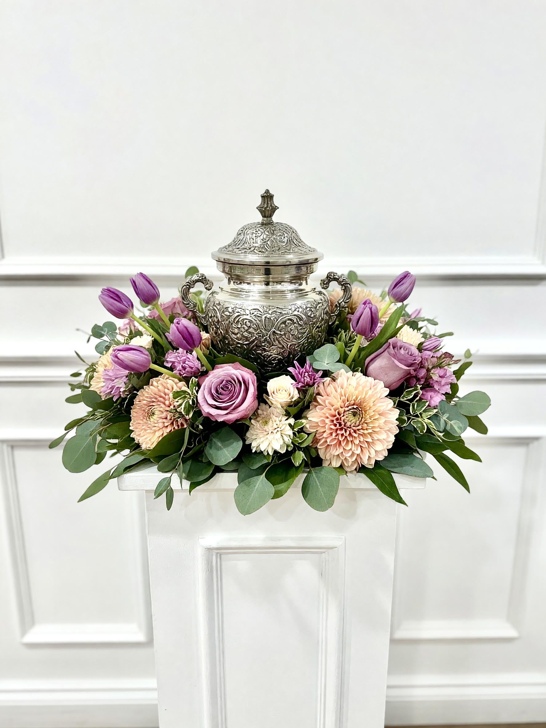 LF424 Lavender Memories Urn Tribute - A soft and graceful urn arrangement featuring lavender roses, purple tulips, blush dahlias, delicate seasonal blooms, and lush eucalyptus.  Designed to surround a cherished urn with beauty and serenity.  This elegant tribute celebrates a life remembered with love, warmth, and lasting affection. 