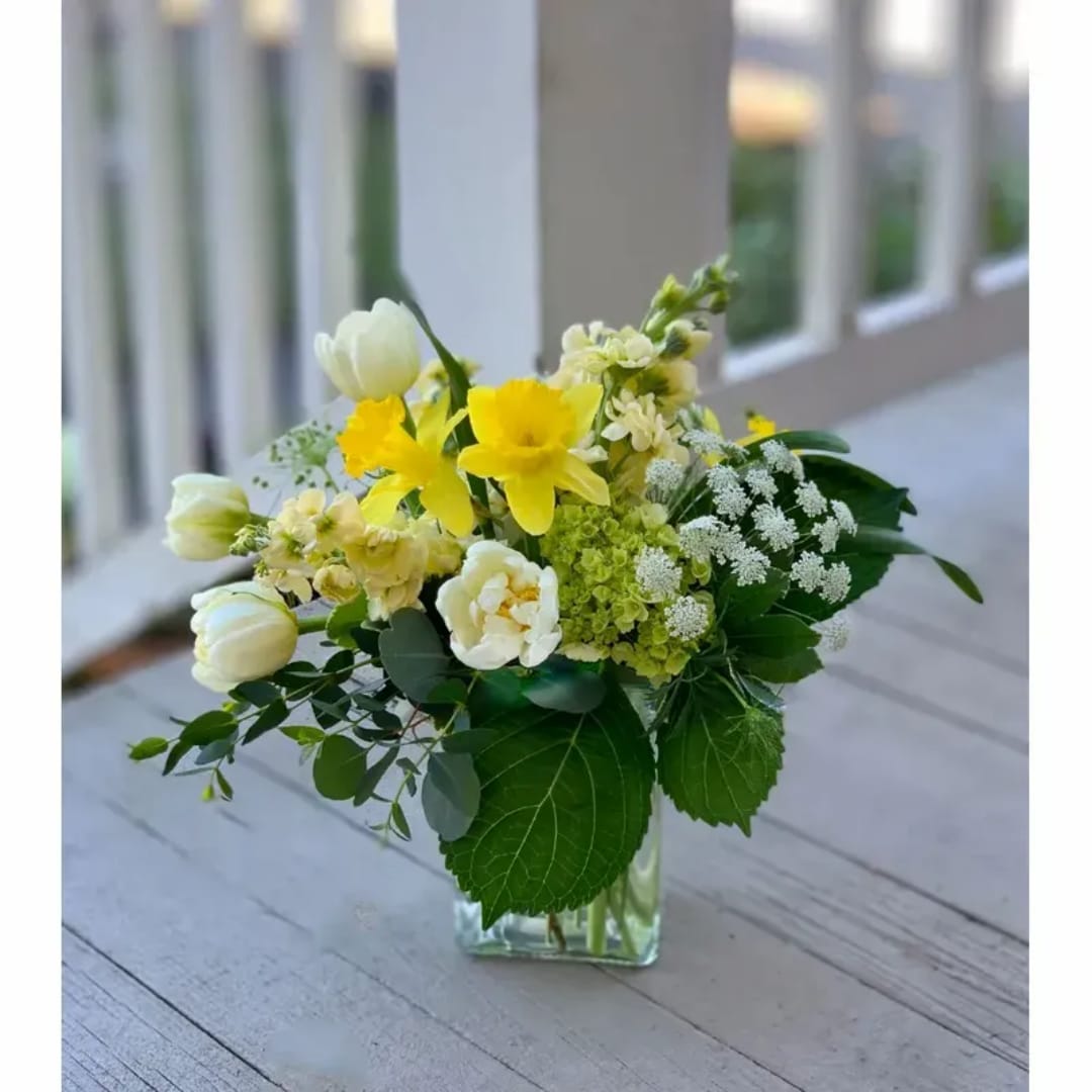 Yellow and white flowers arranged in a clear glass vase
