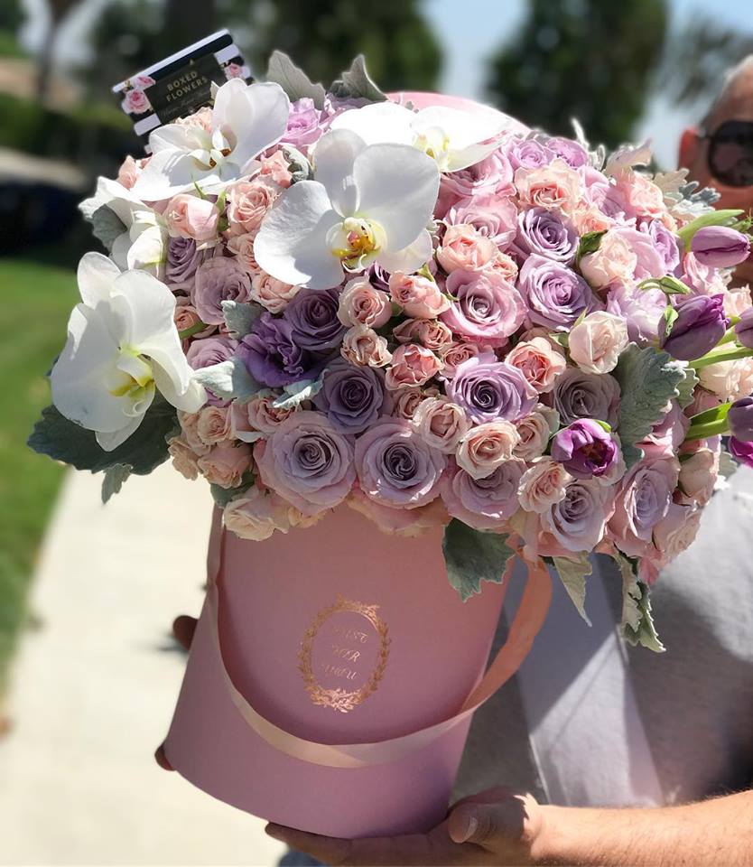 Pink and lavender rose bouquet in a pink hatbox with white orchids