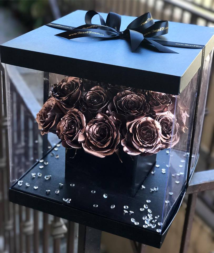 Rose Gold Goodness - This is a unique and one of a kind arrangement that will leave anyone speechless. Black surprise box filled with rose gold sprayed roses.