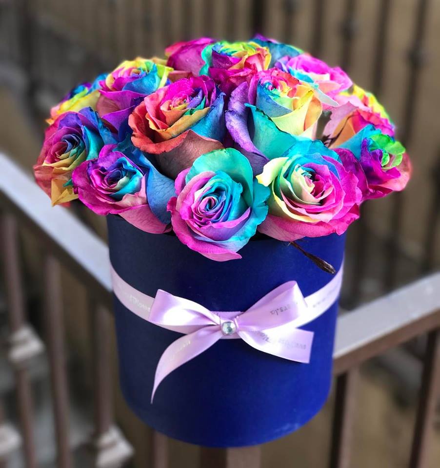 Rainbow-colored roses in a blue hatbox with a pink ribbon