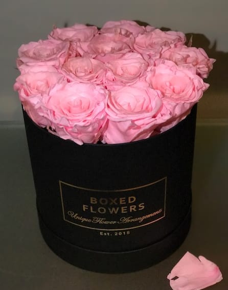 Pink roses arranged in a black round box