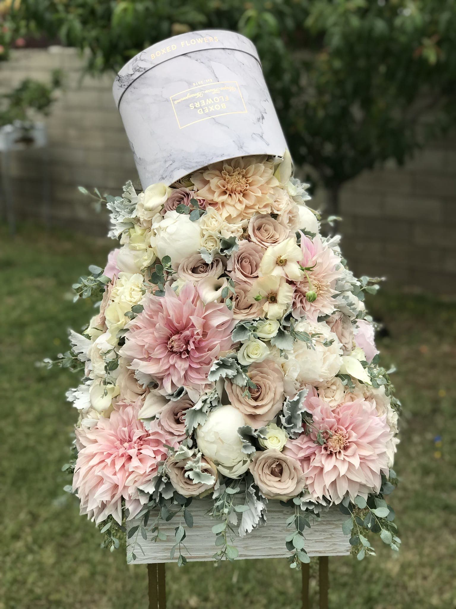 Pastel floral arrangement in a hatbox with pink and cream blooms