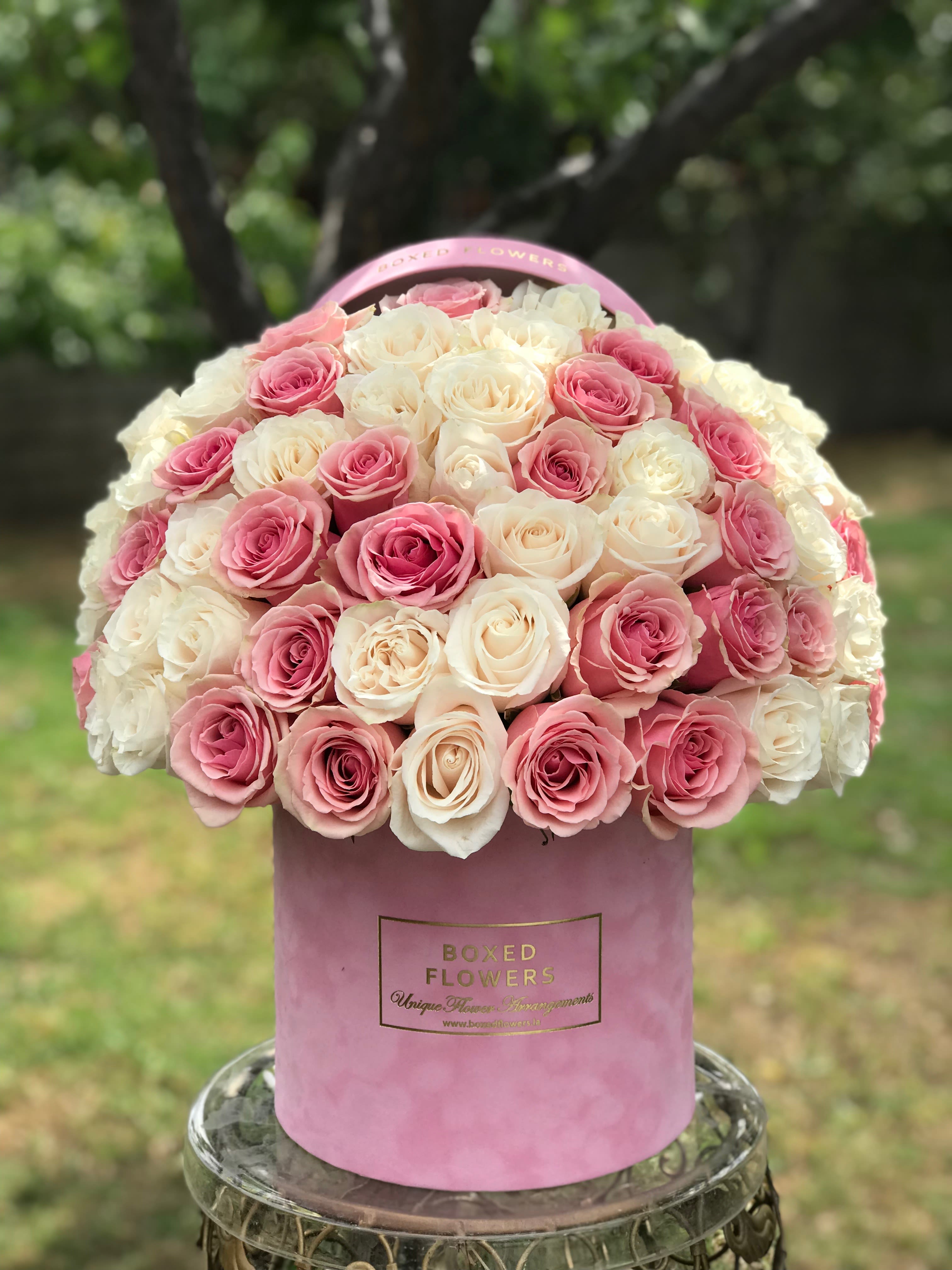 Pink and white roses arranged in a round pink hat box