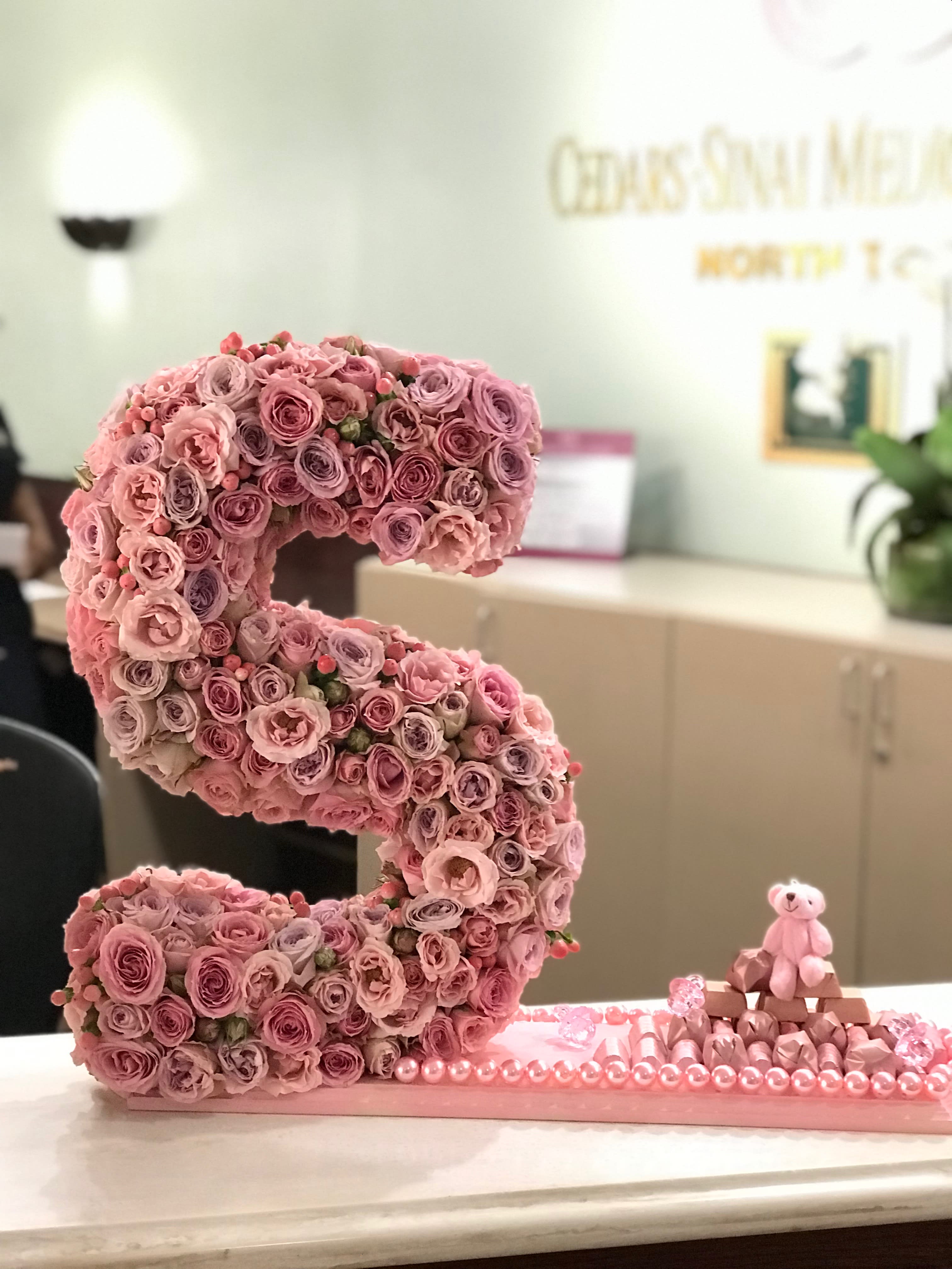 Pink rose letter display with a small teddy bear and chocolates