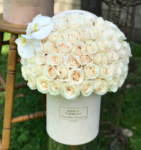 White roses and orchids arranged in a white hat box