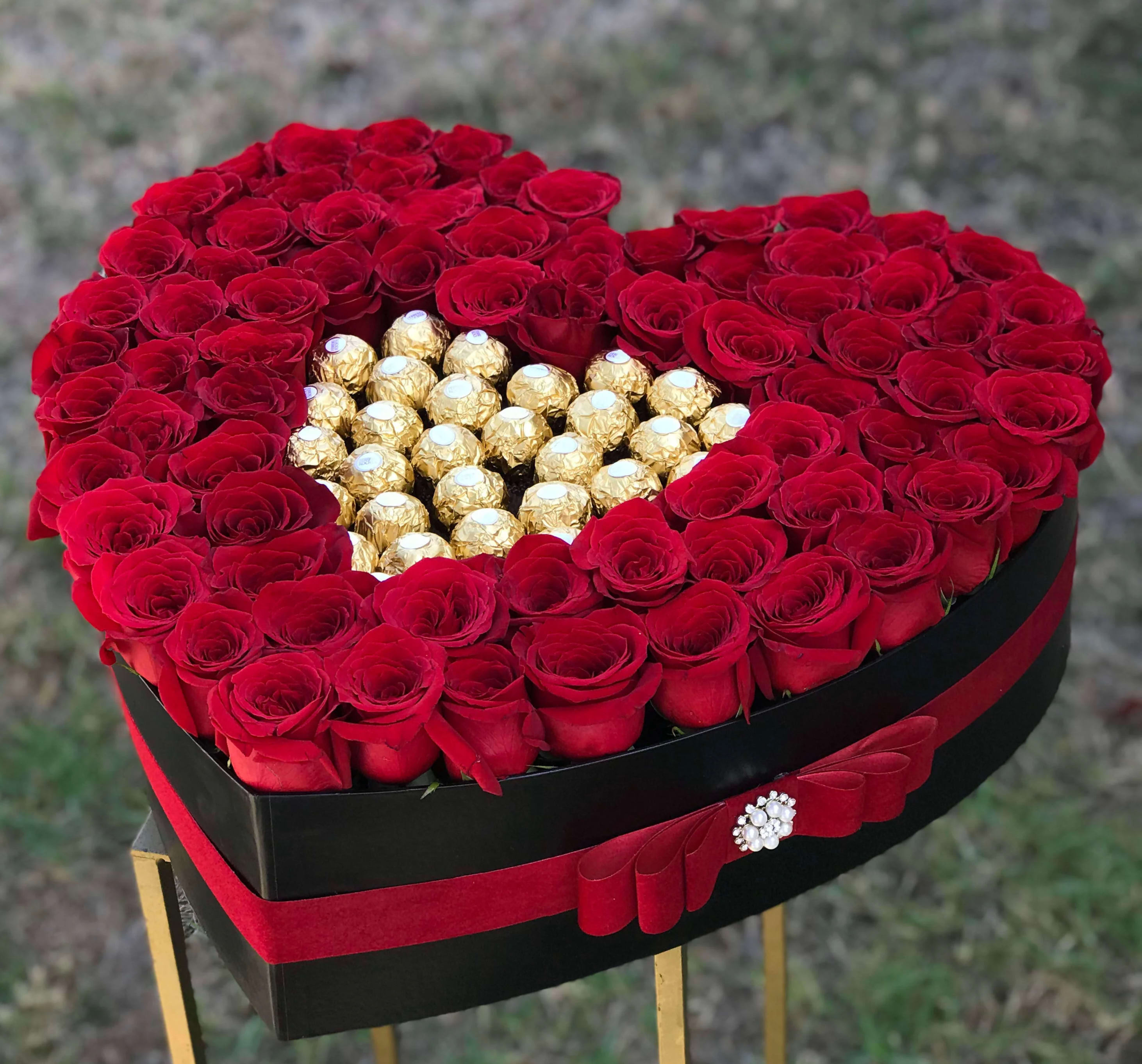 Heart-shaped box of red roses with gold-wrapped chocolates in the center