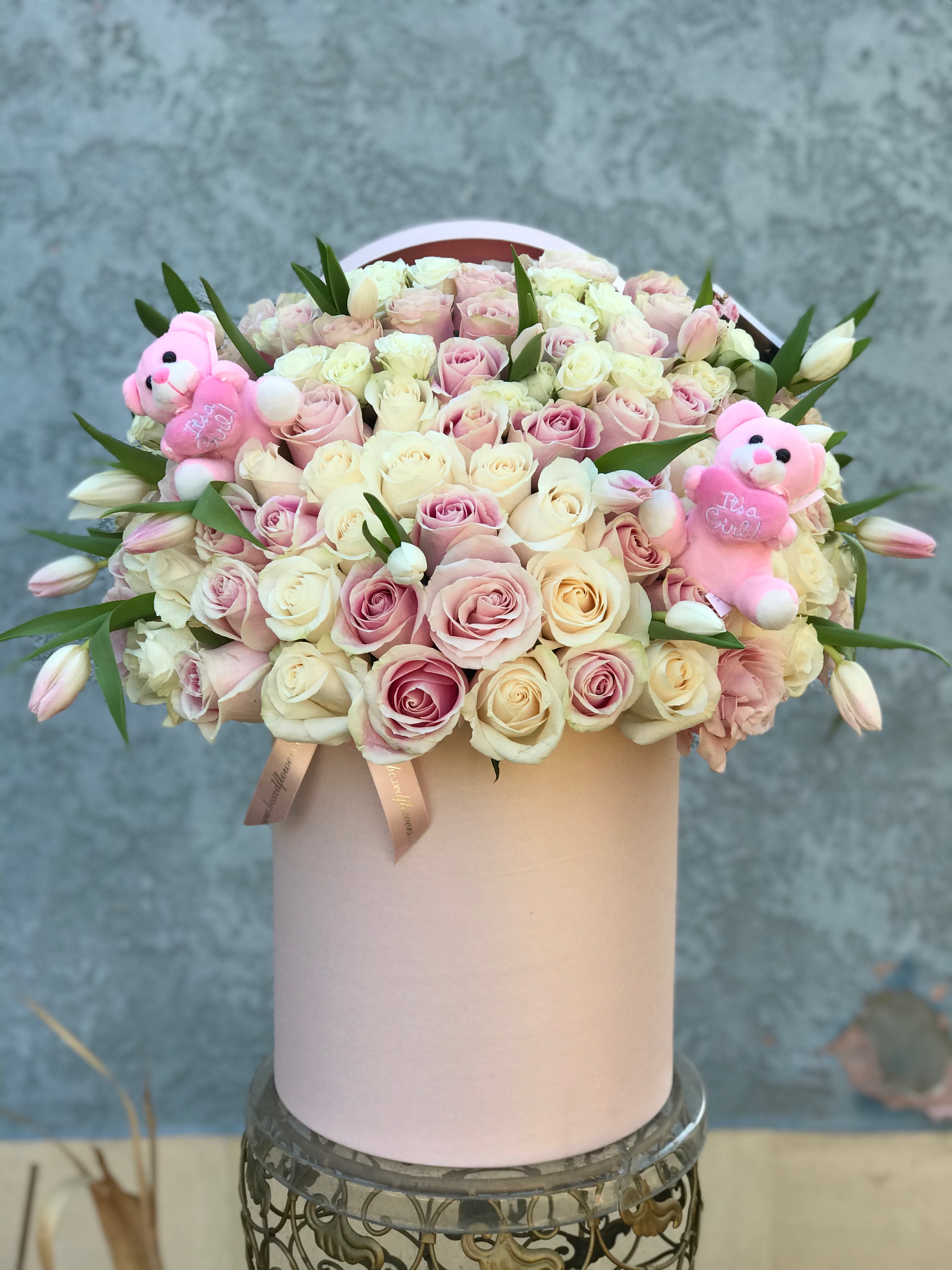 Round box of pale pink and cream roses with two pink teddy bears