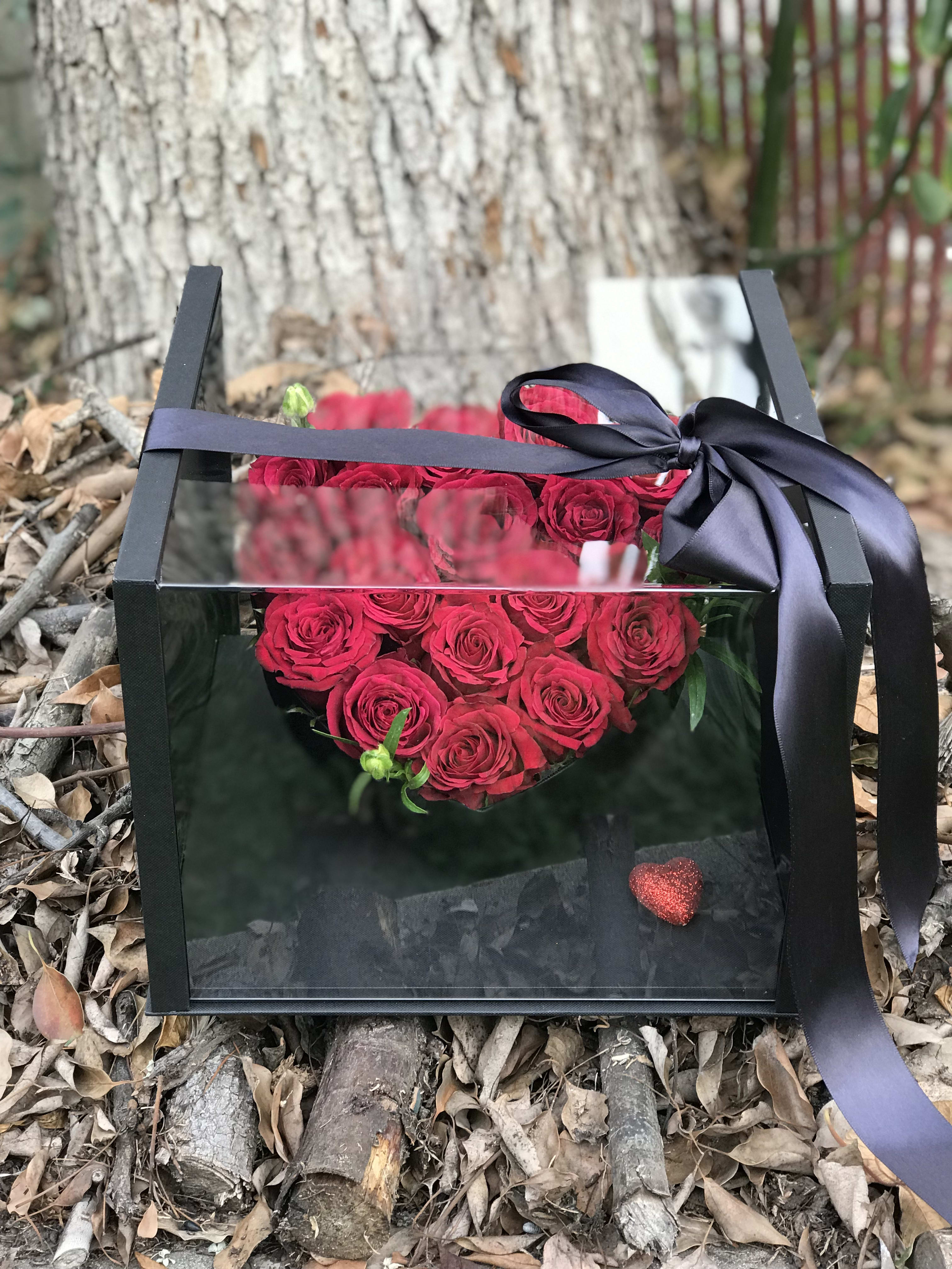 Heart-shaped box of red roses tied with a black ribbon