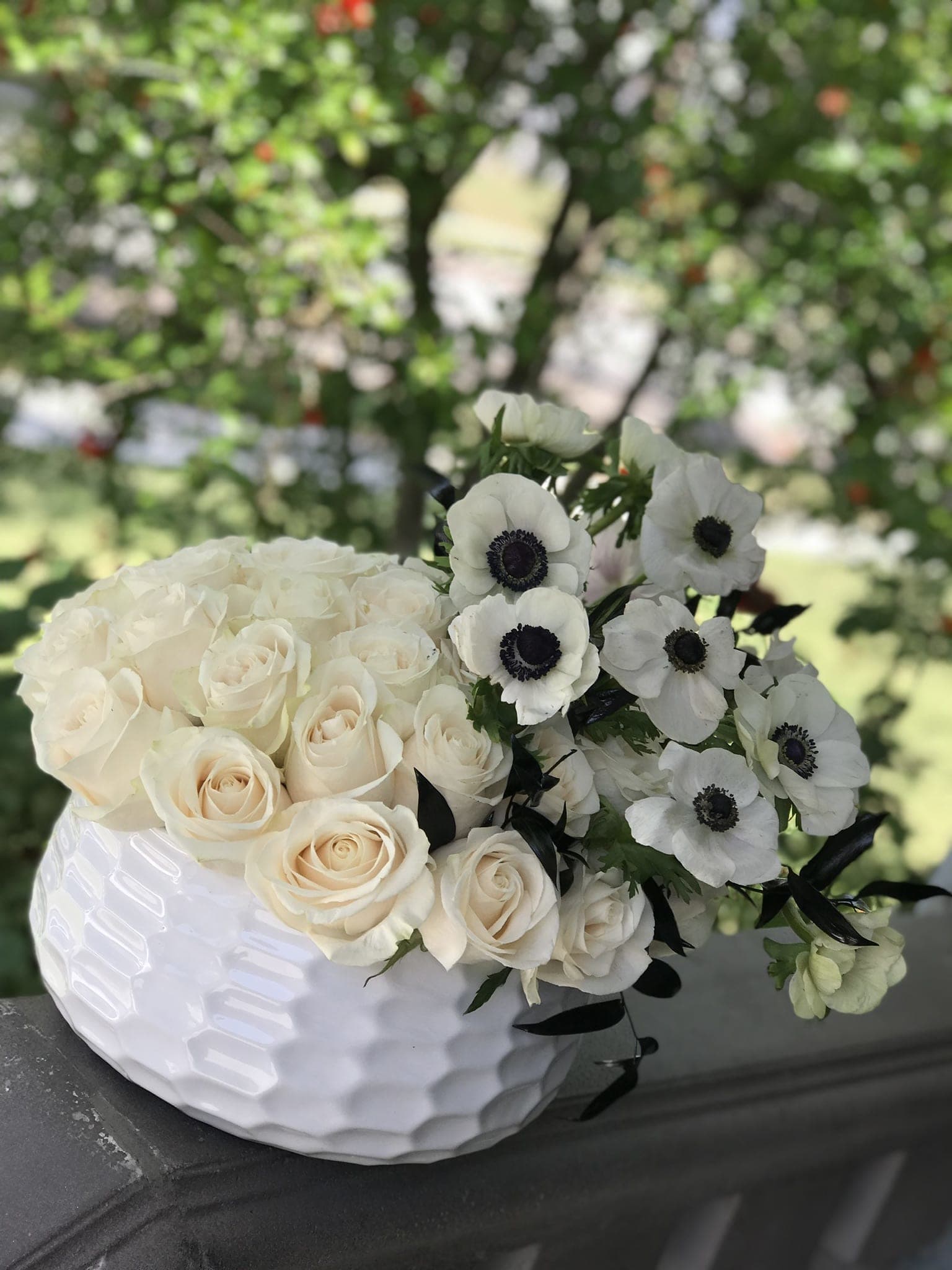 White roses and white anemones arranged in a white vase
