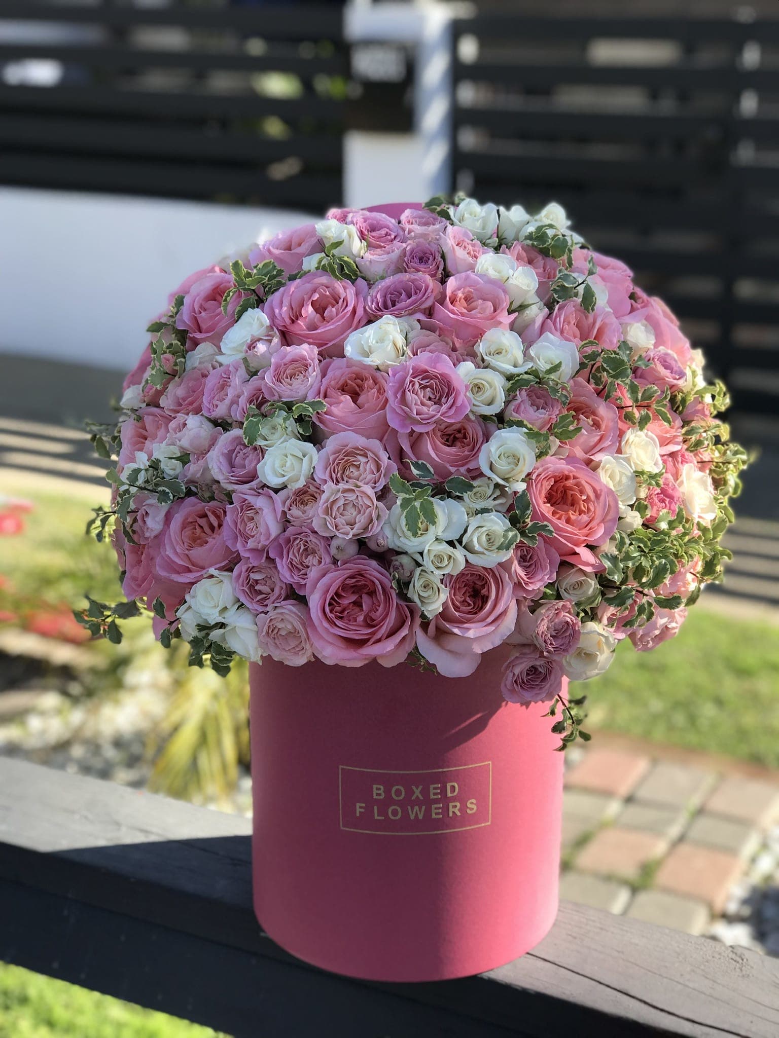 Pink and white roses arranged in a round hatbox