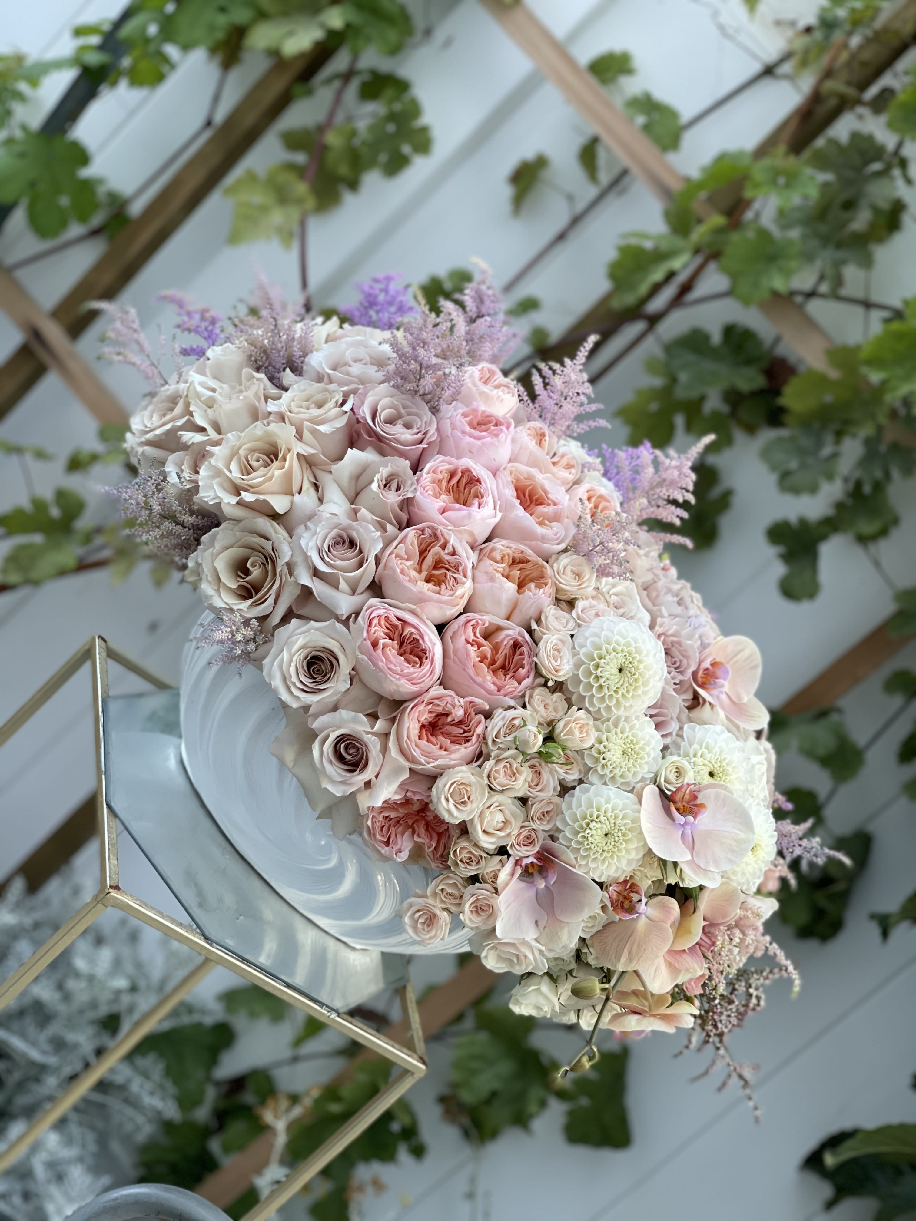 Pastel bouquet of roses, orchids, and white blooms on a mirrored stand