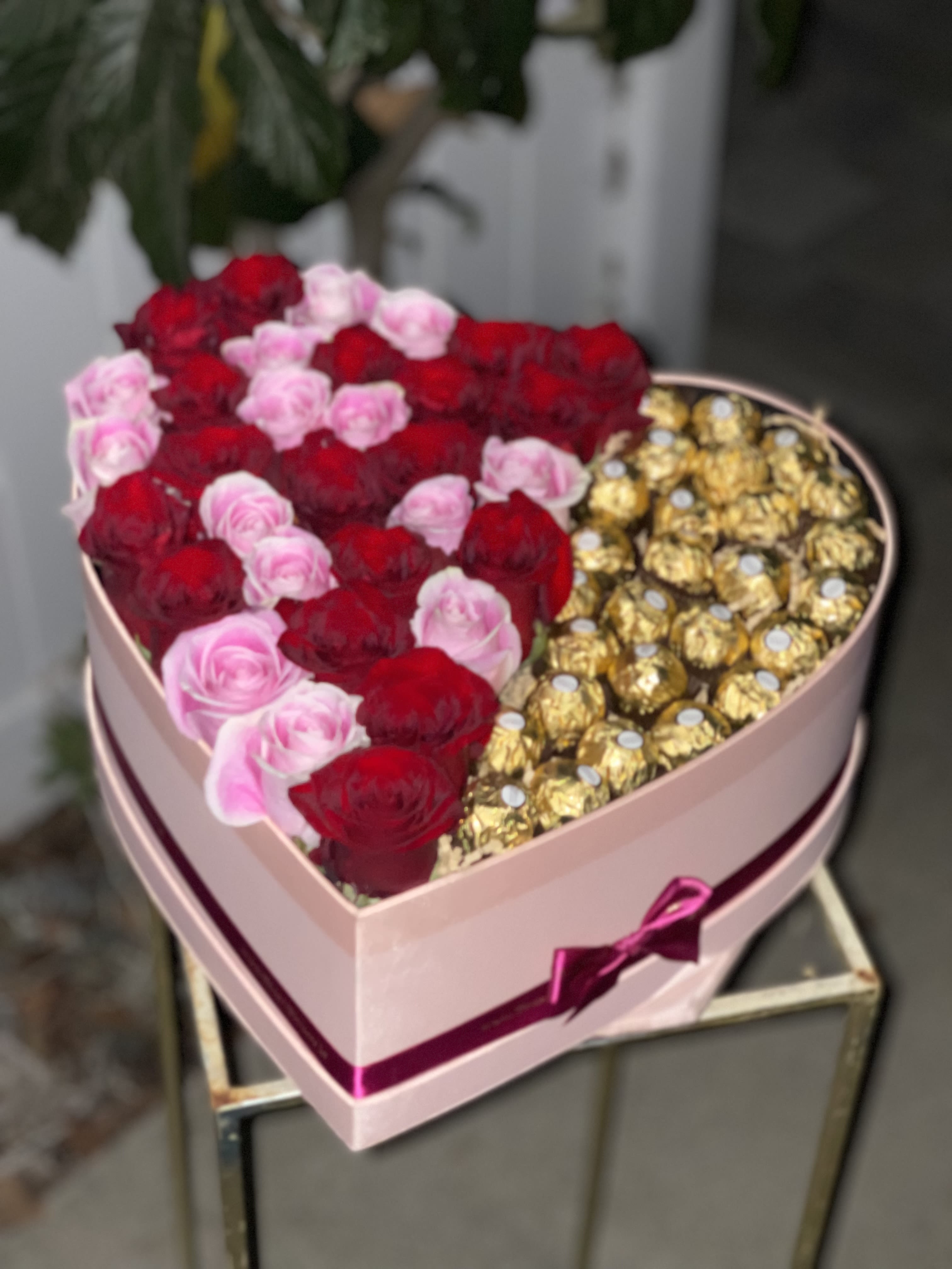 Heart-shaped box with red and pink roses and gold-wrapped chocolates