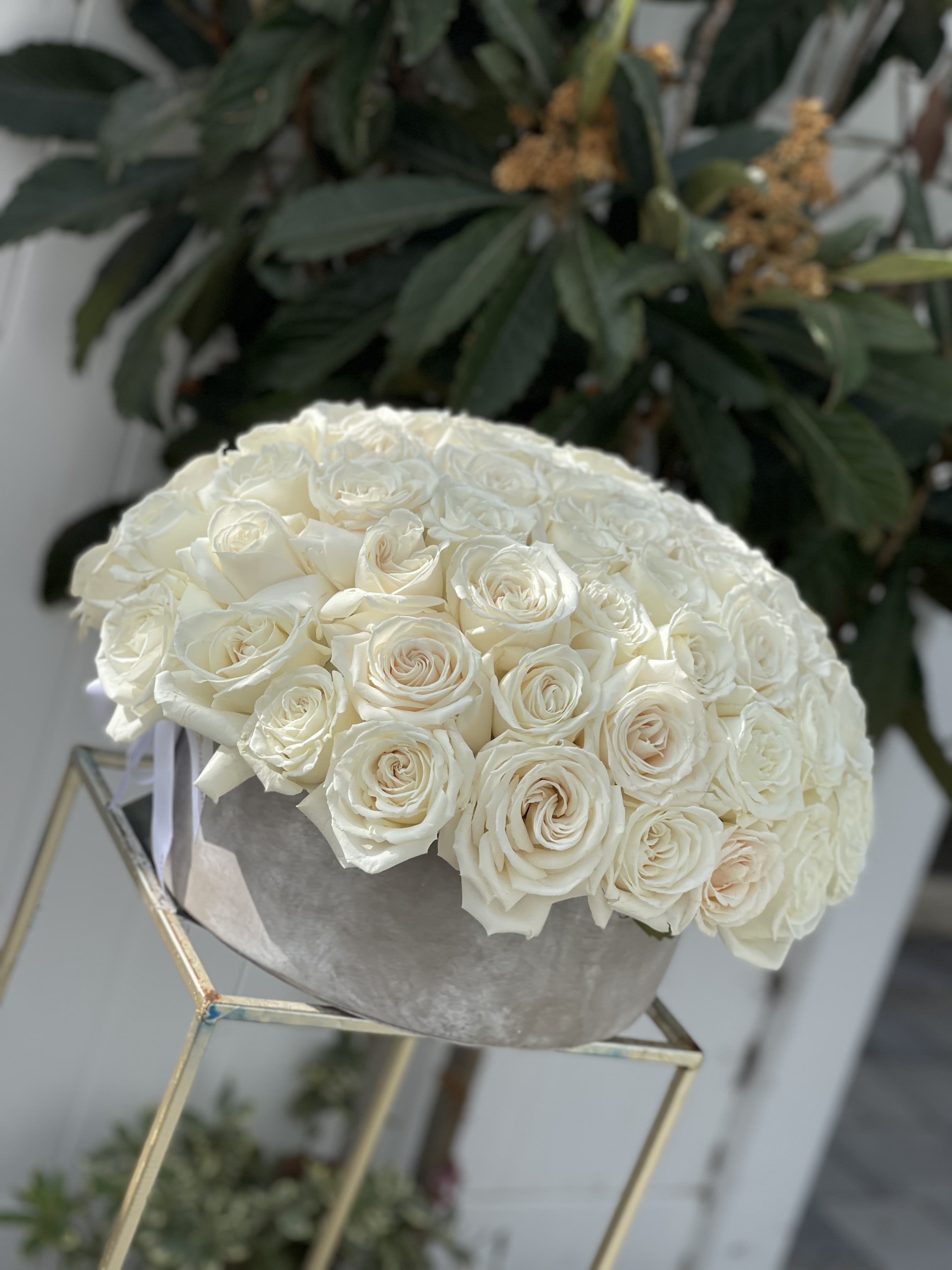 Round bouquet of white roses in a gray box