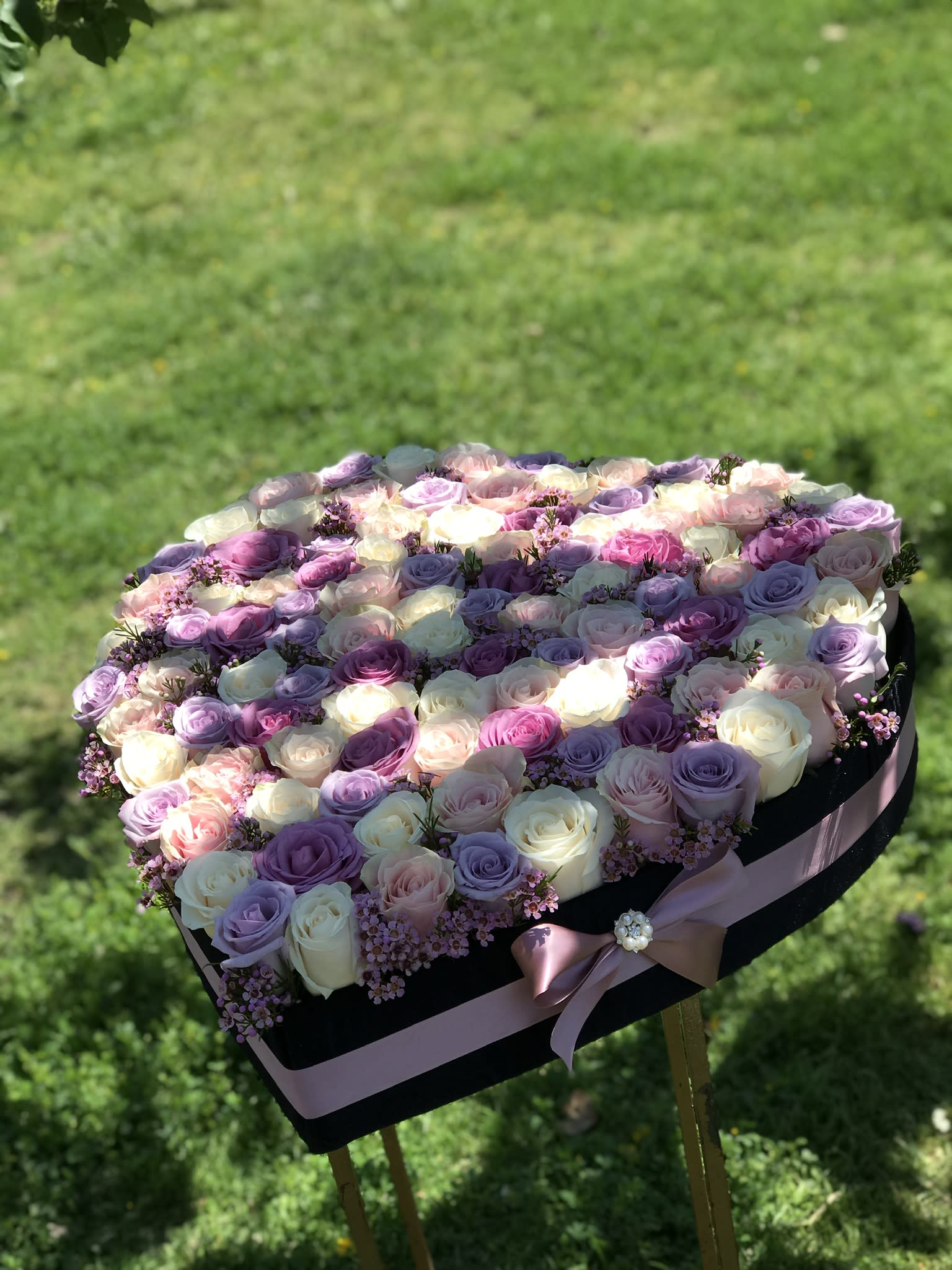 Heart-shaped box filled with pastel roses and small pink flowers