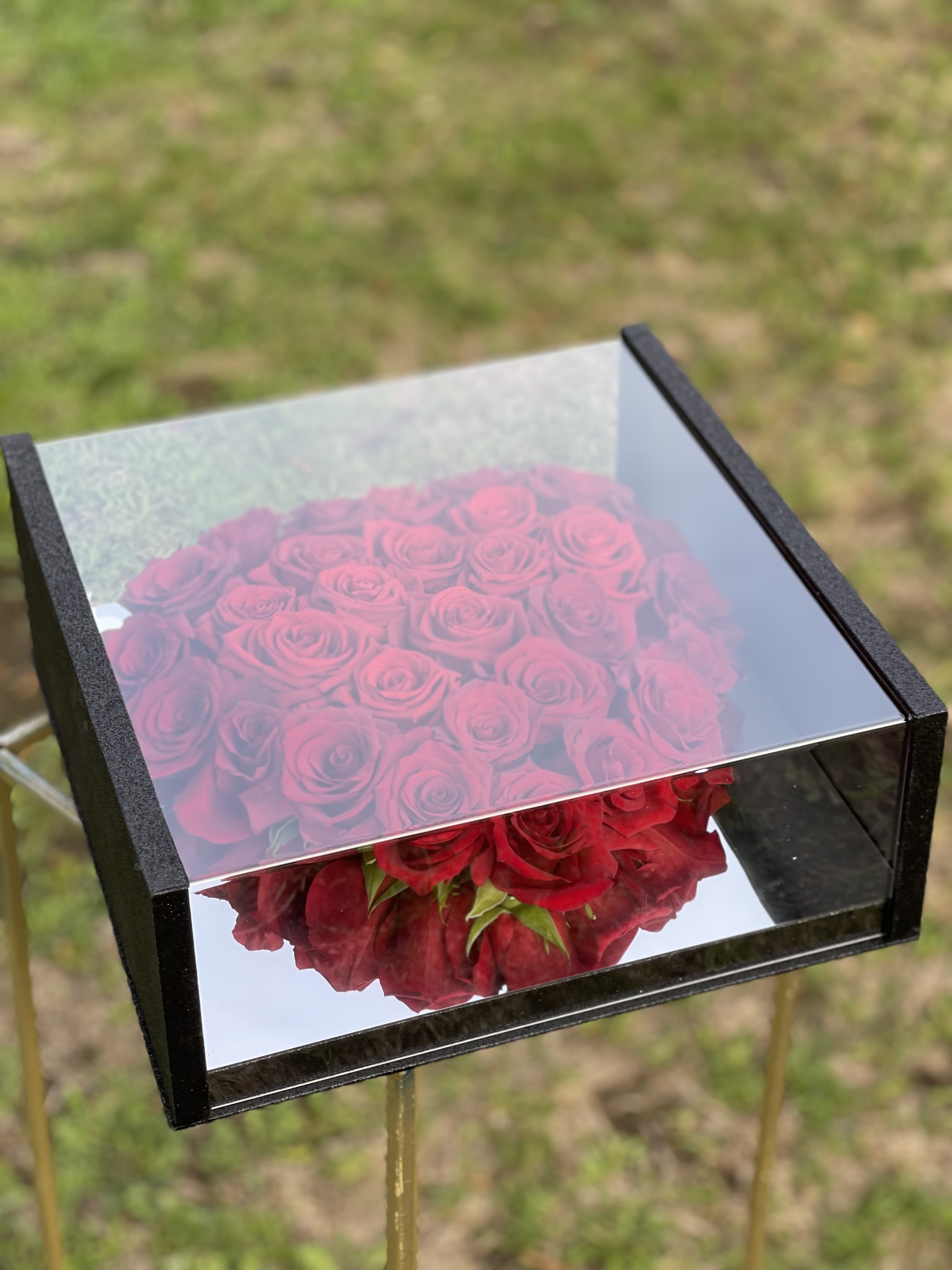 Box of red roses with a mirrored lid outdoors