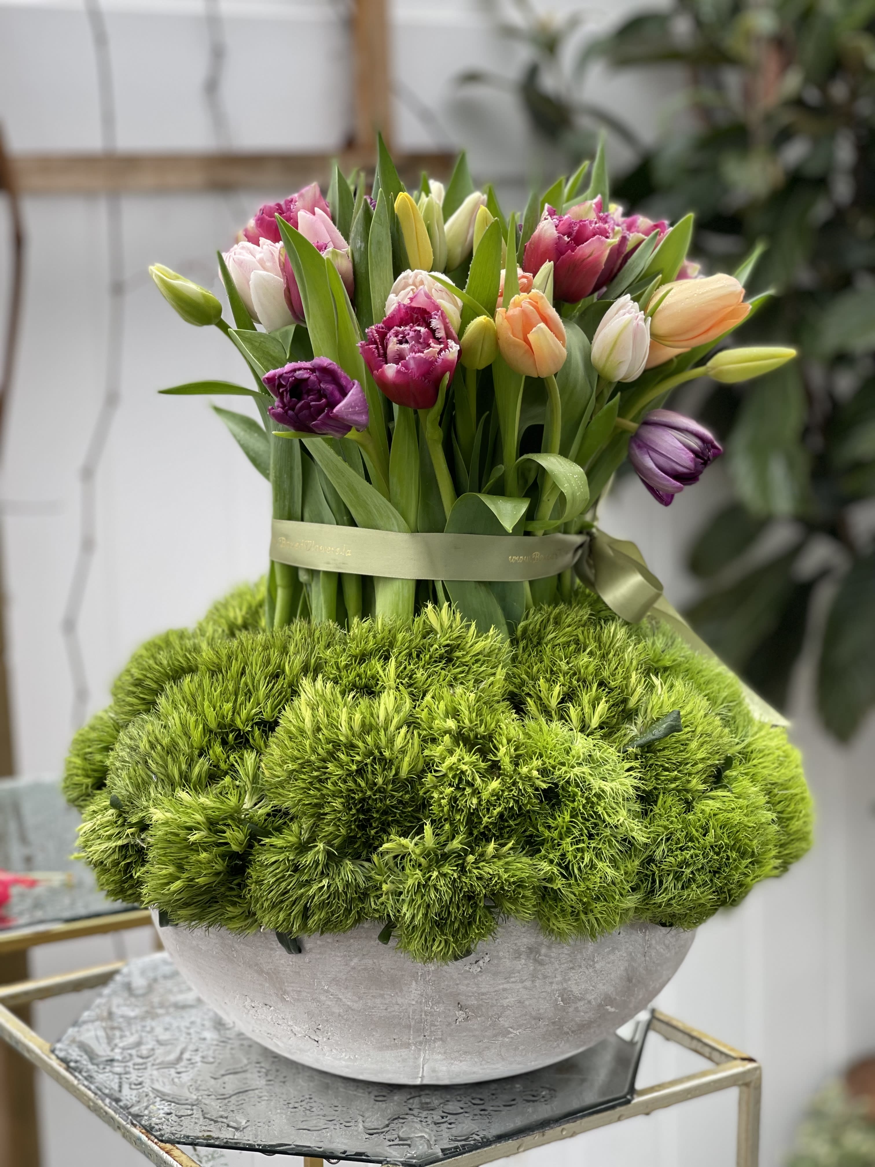 Bouquet of multicolored tulips in a round gray vase with green moss