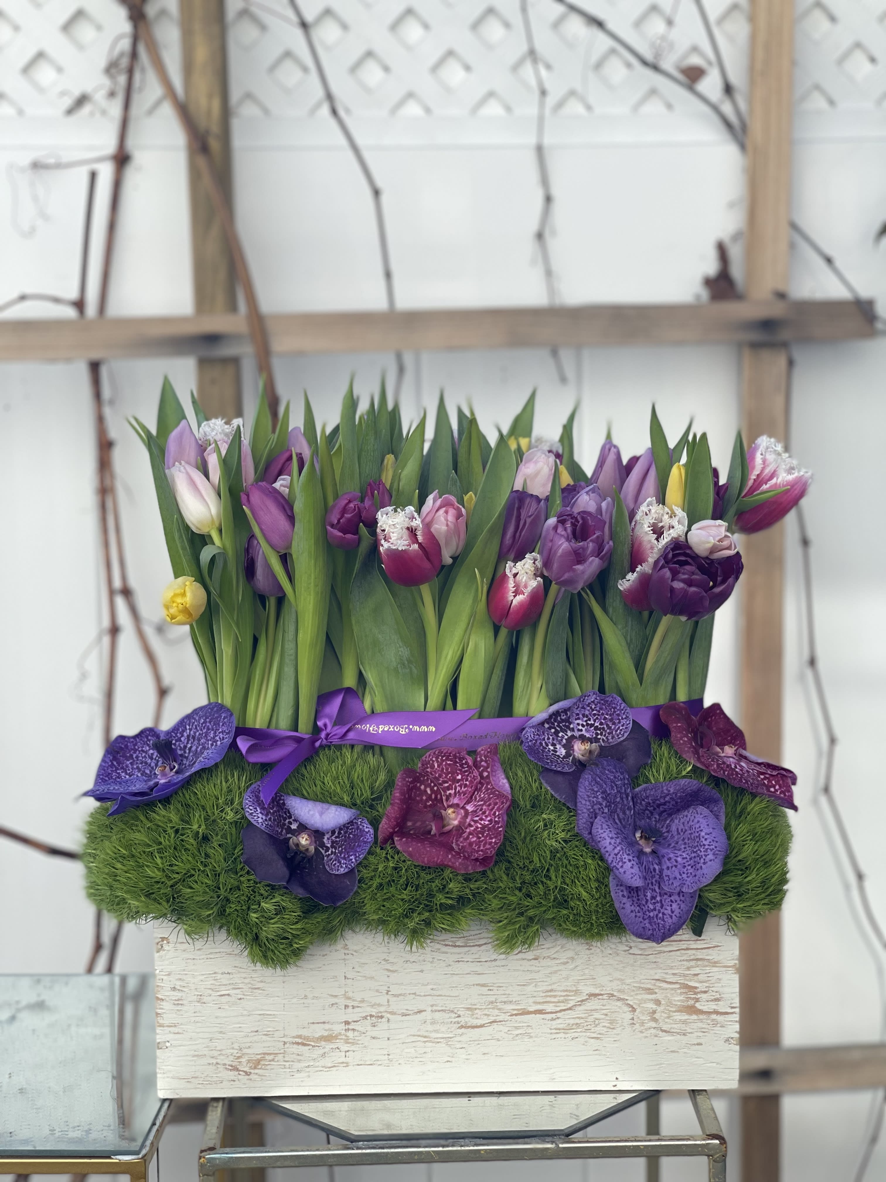 Purple and pink tulips with orchids in a rectangular planter