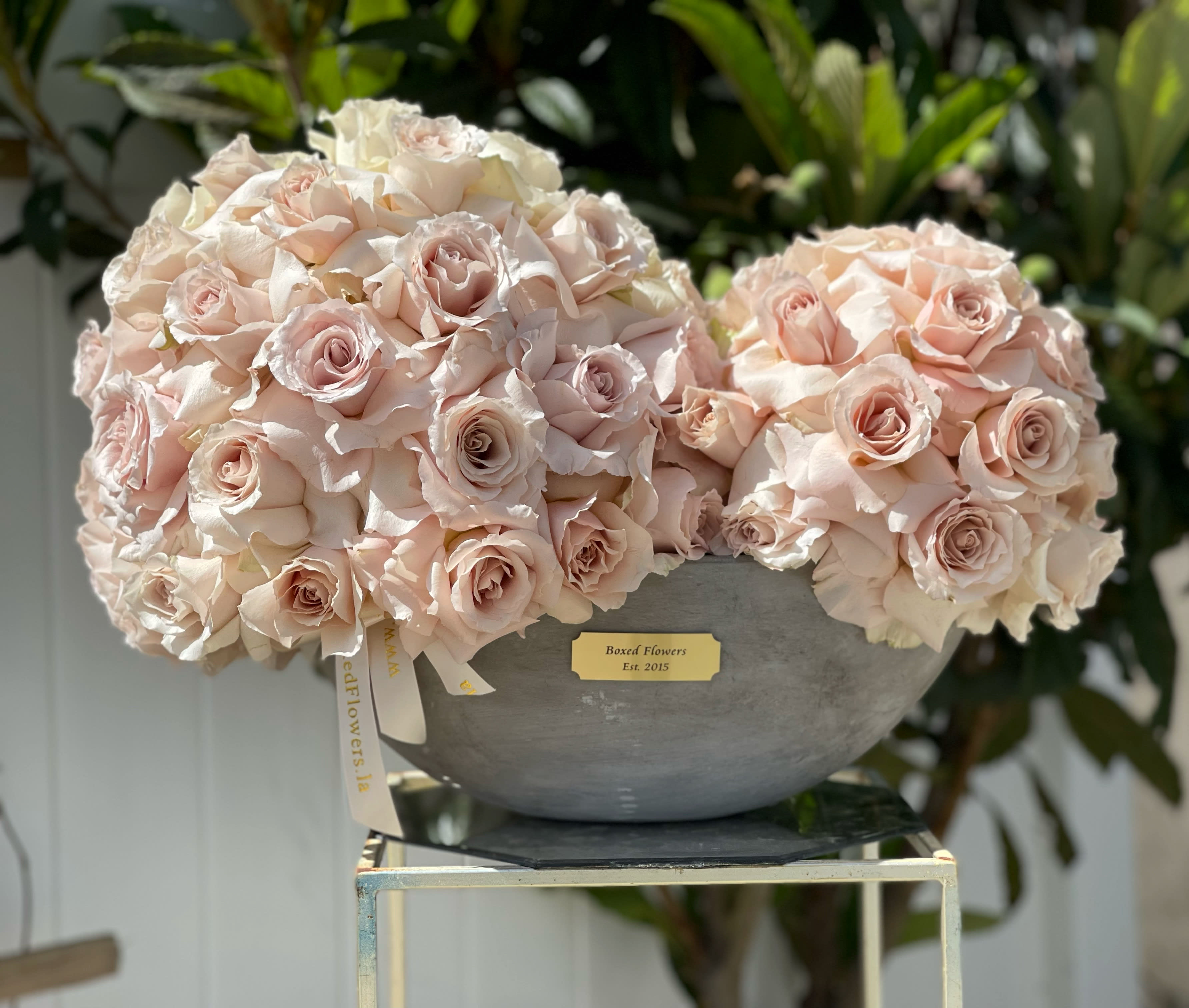 Two pale pink rose arrangements in a gray bowl vase