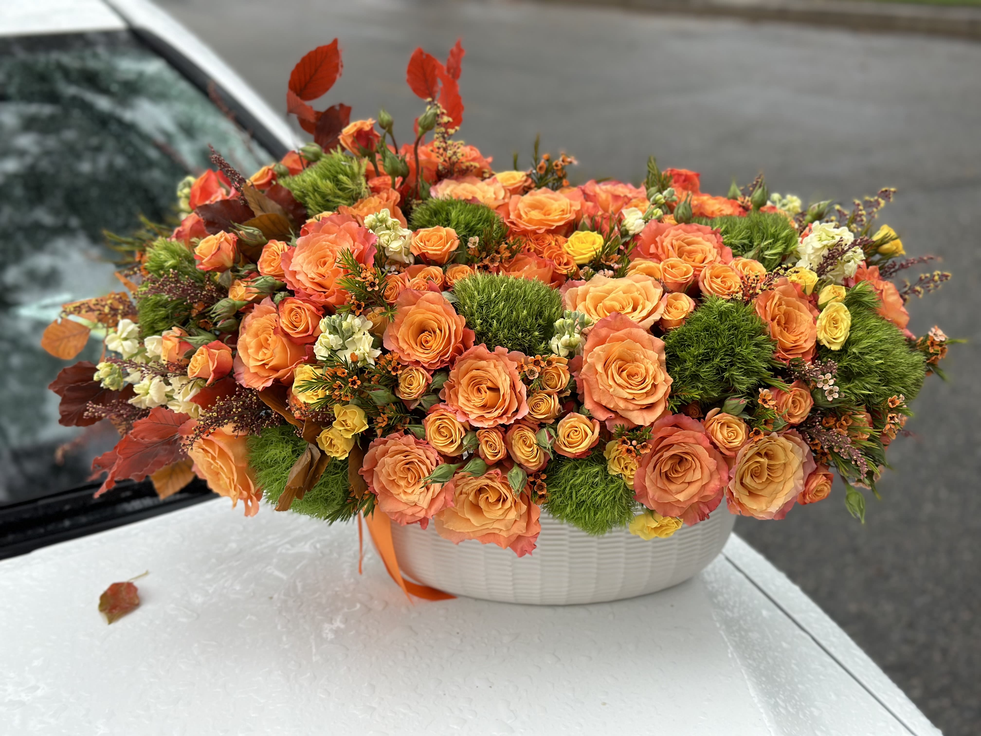 Orange rose arrangement in a white oval container