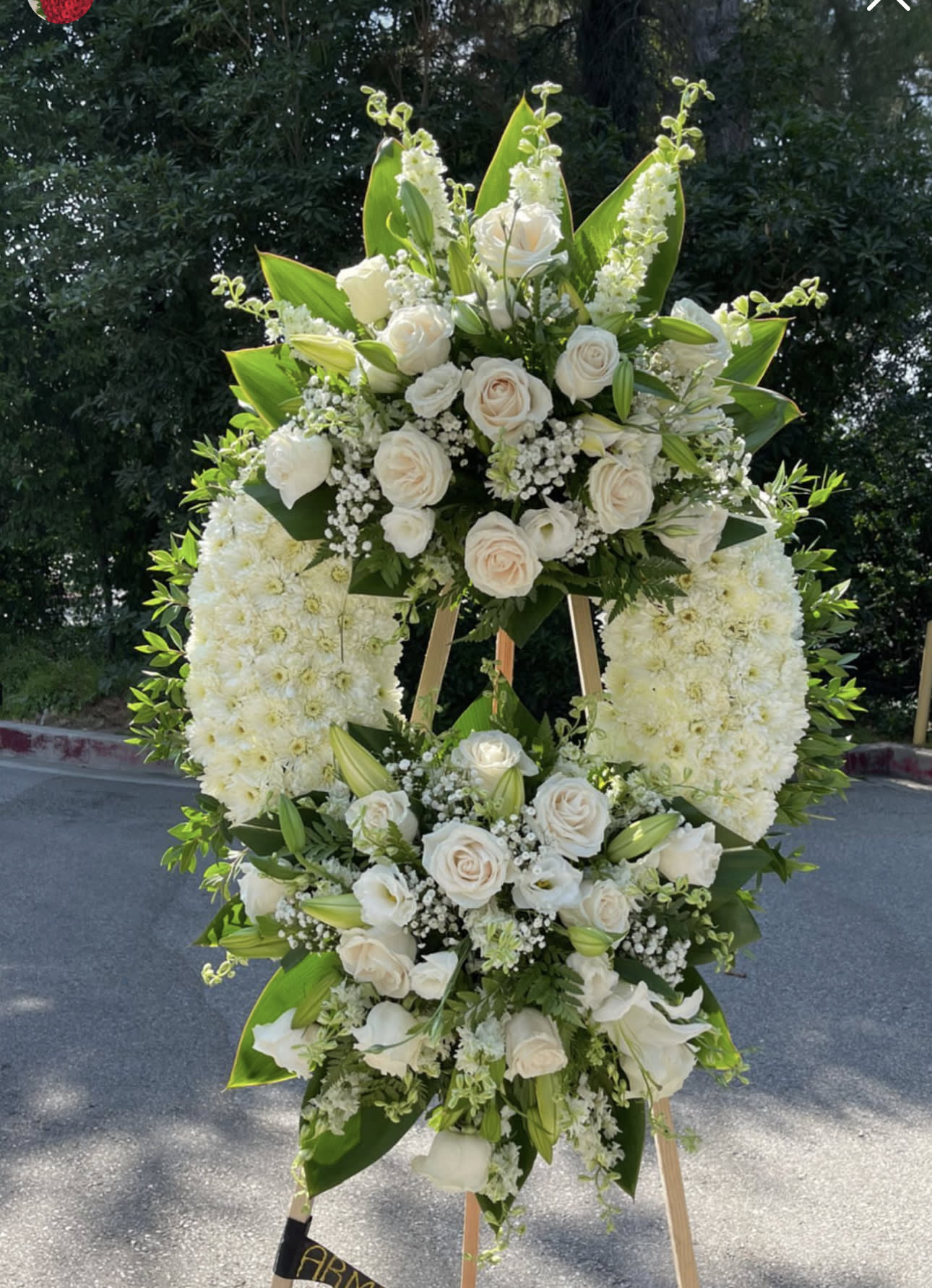 Large white floral standing spray on an easel with roses and lilies