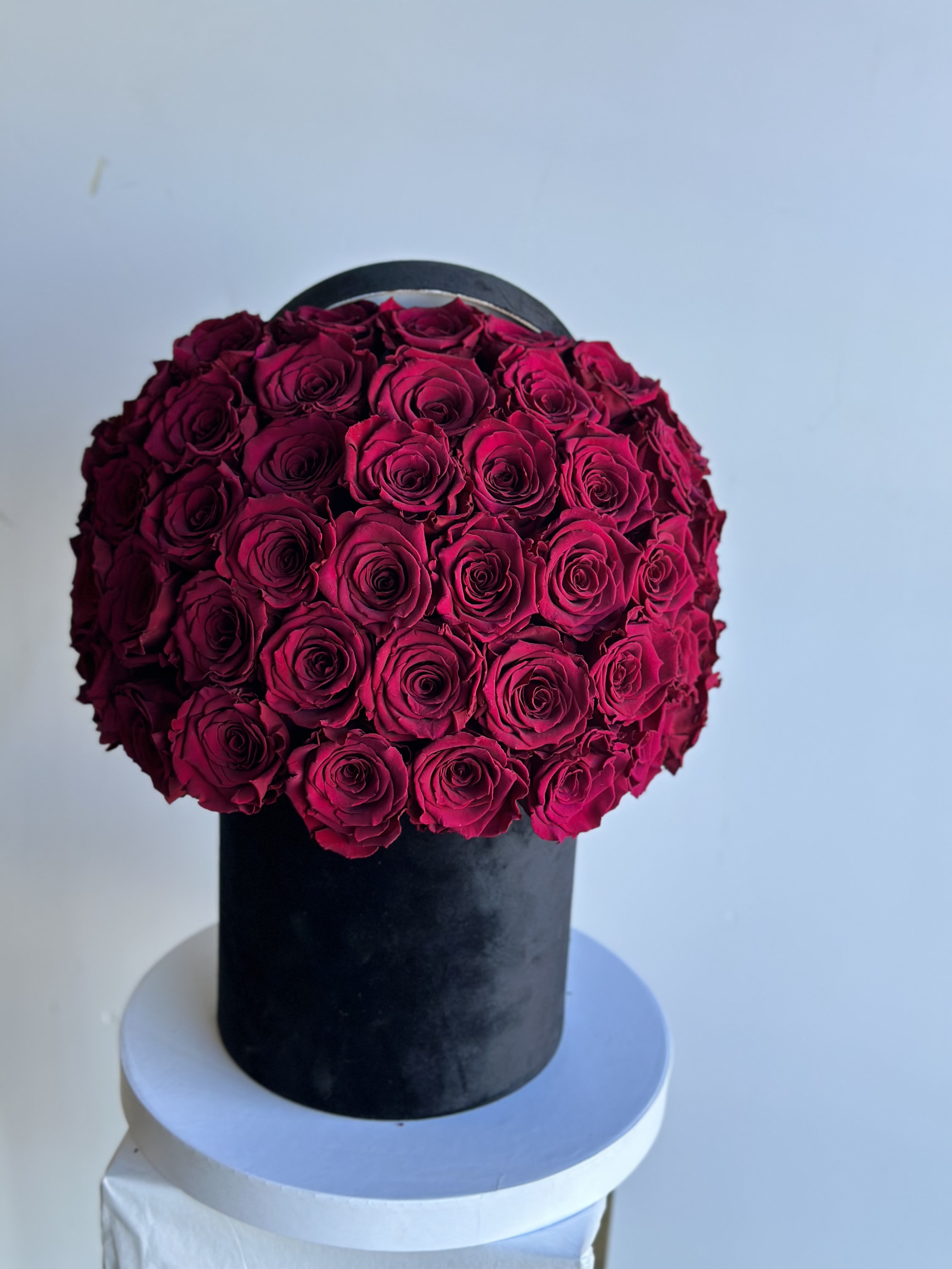 Round arrangement of deep pink roses in a black box