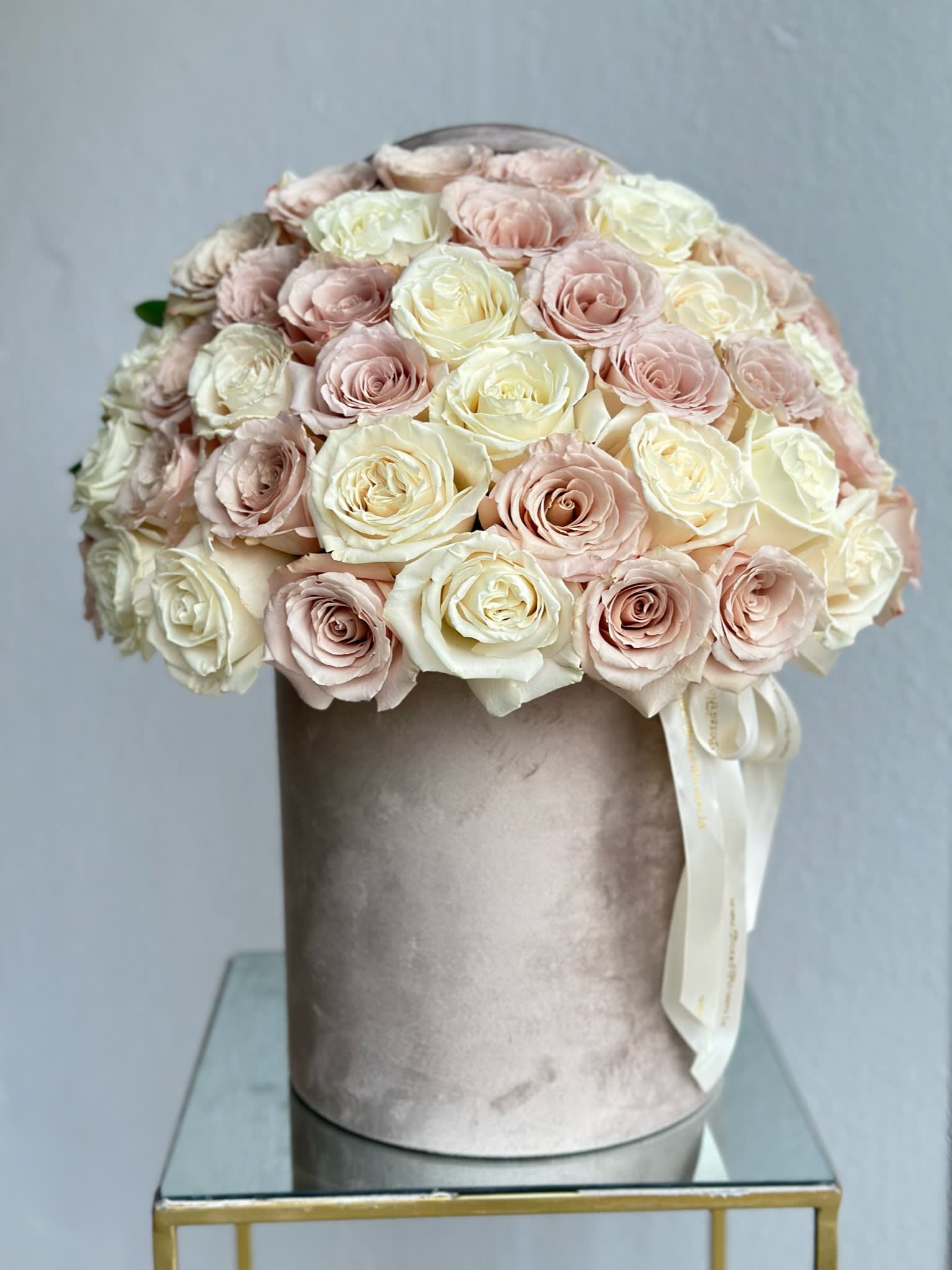 Round bouquet of pale pink and cream roses in a velvet hatbox