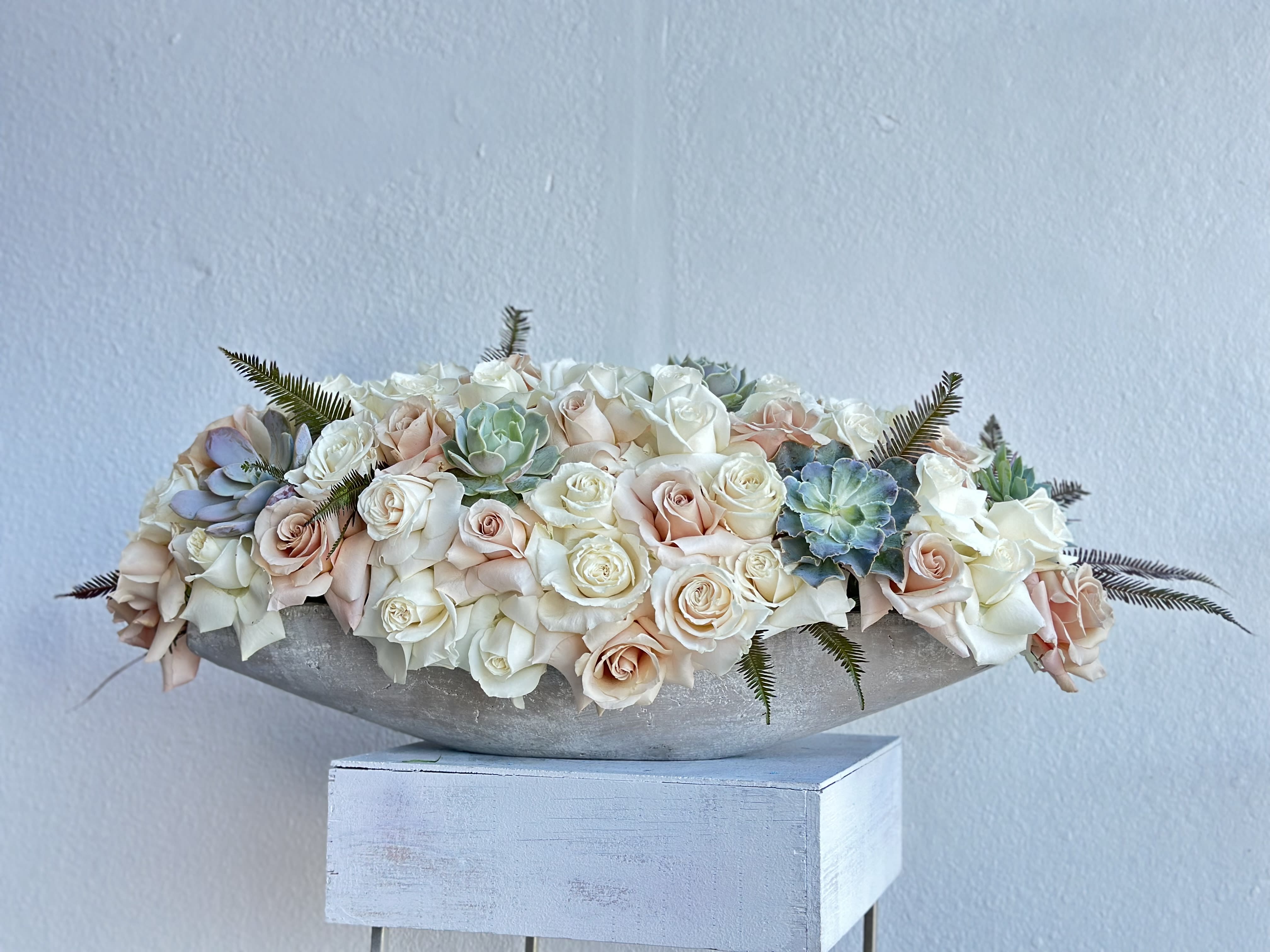 Low arrangement of pale roses and succulents in a shallow bowl