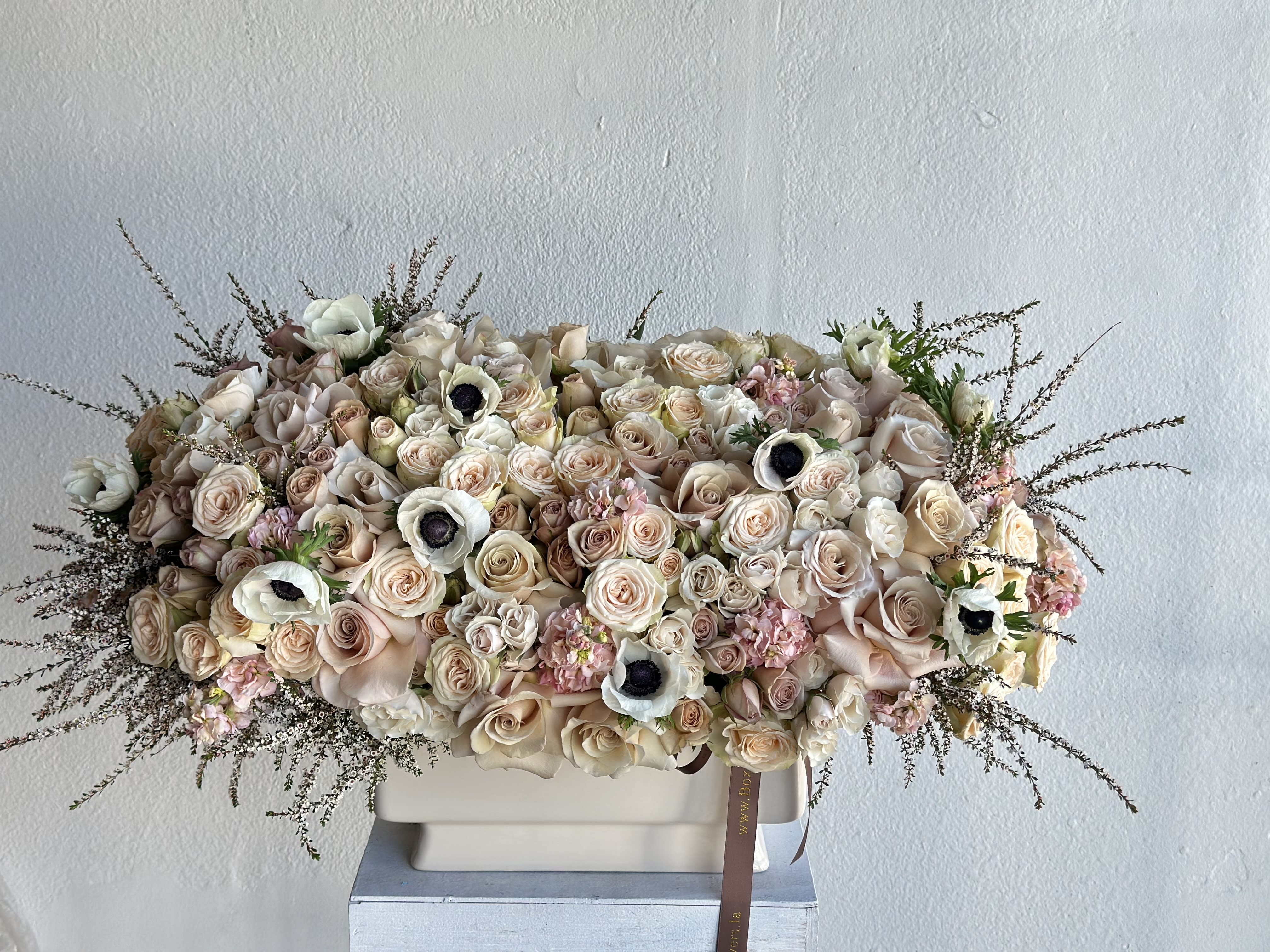 Large pastel bouquet of roses and white anemones in a rectangular vase