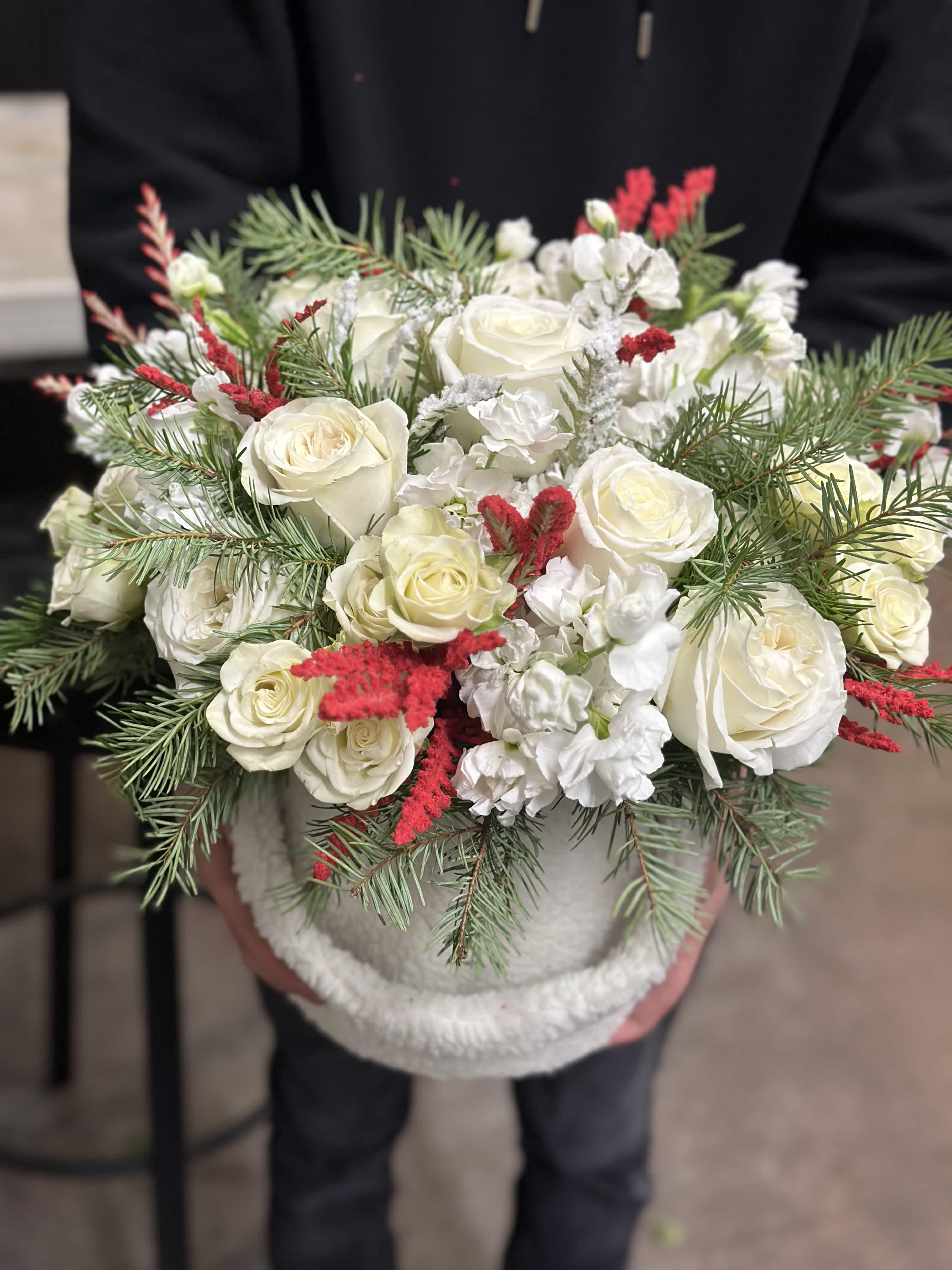 White roses with red accents in a round container