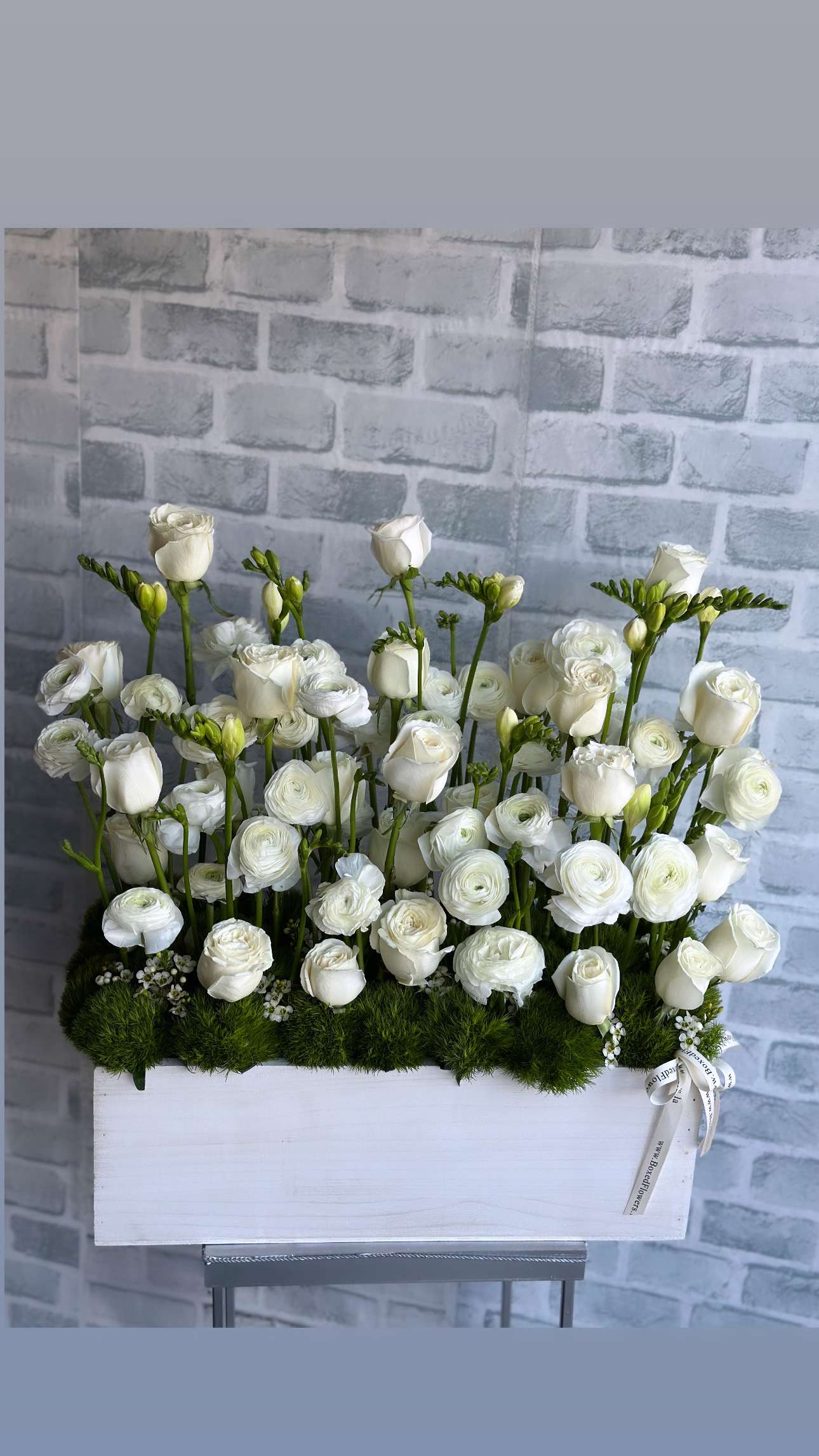 White roses and ranunculus arranged in a white box