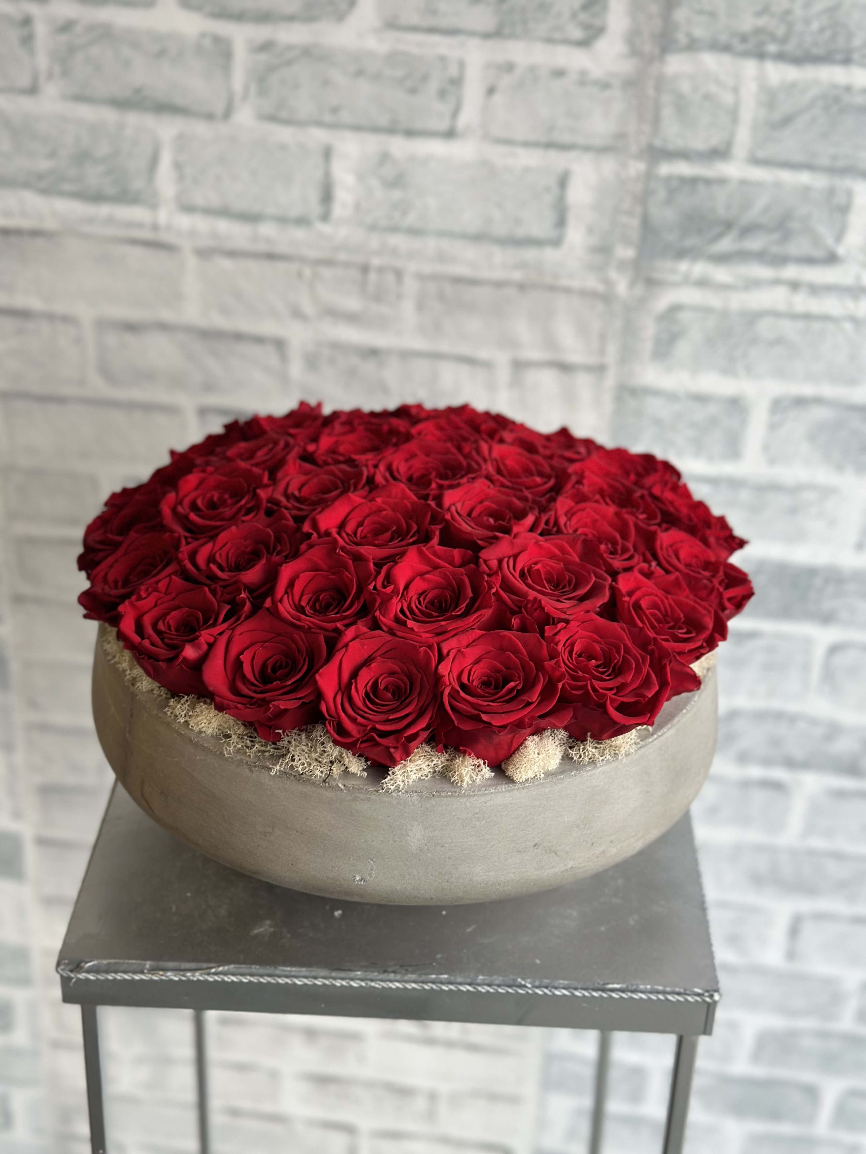 Round arrangement of red roses in a low gray bowl