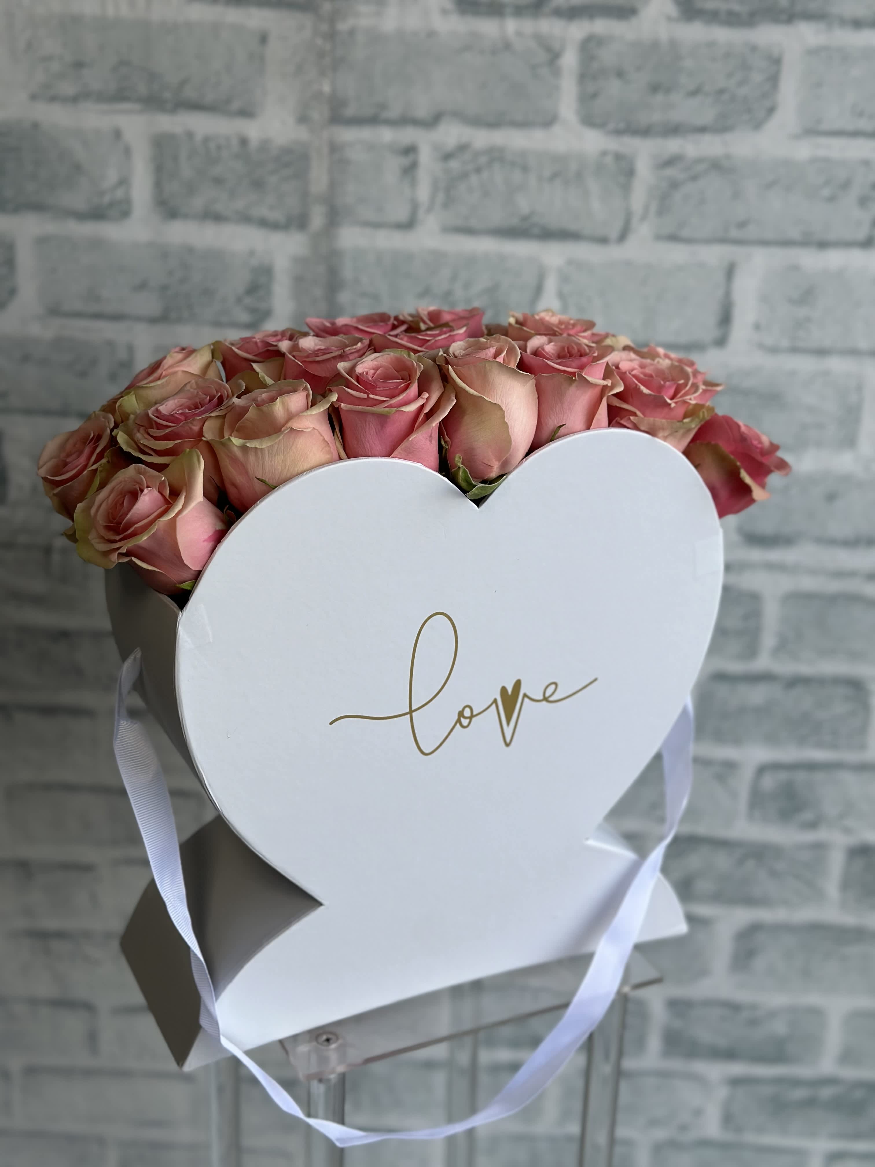 Pink roses in a white heart-shaped box with a ribbon