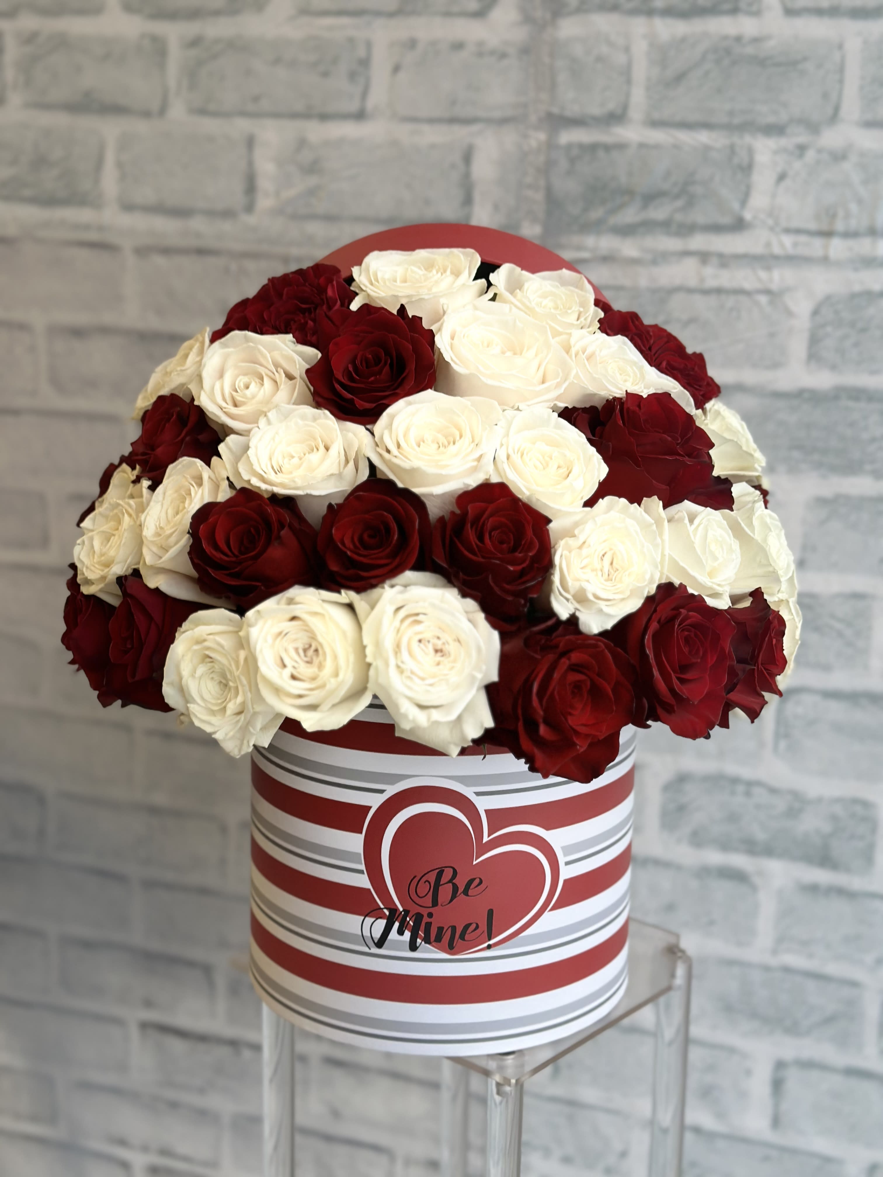 Red and white roses in a striped heart box with "Be Mine" text