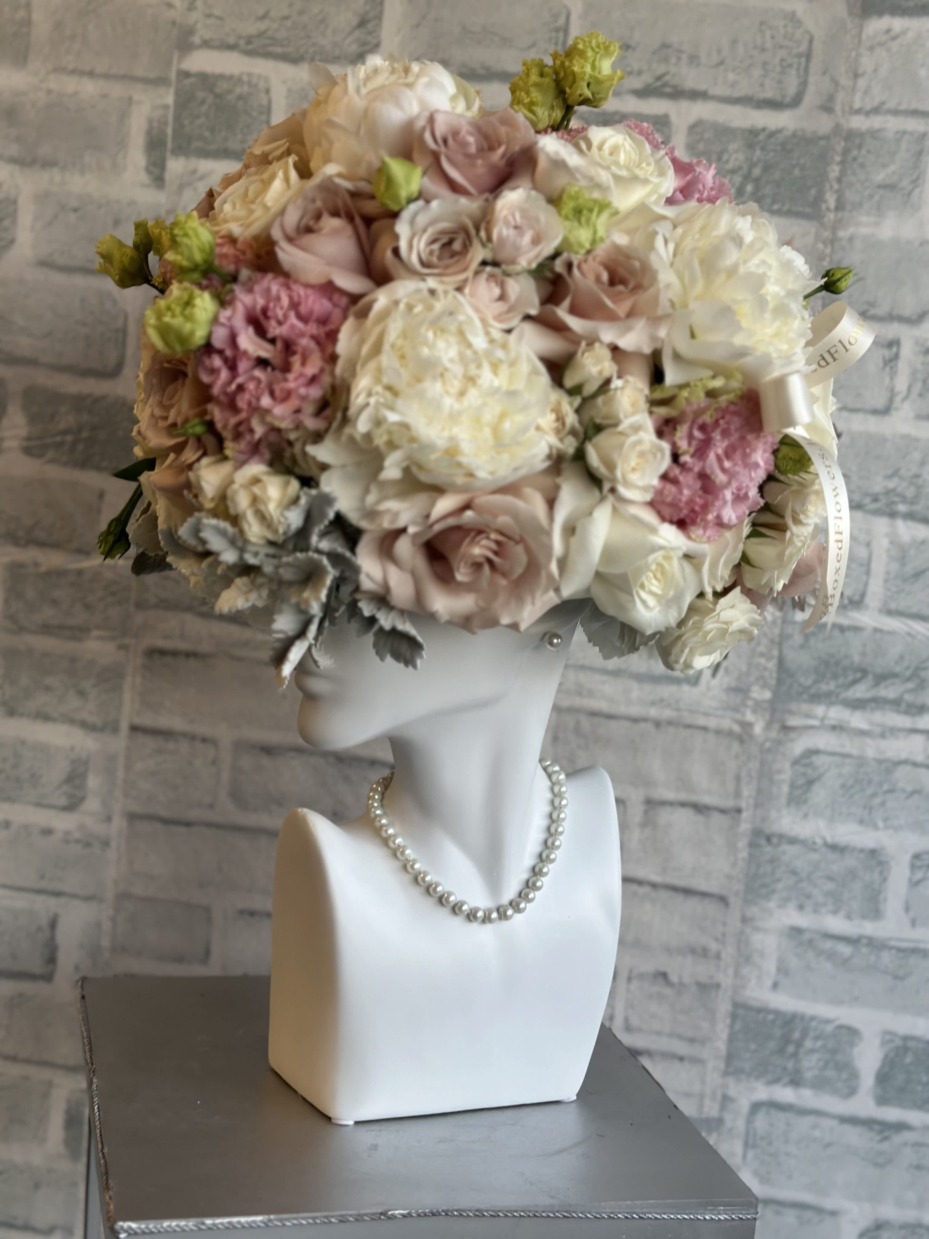 Pastel rose bouquet arranged on a white mannequin bust